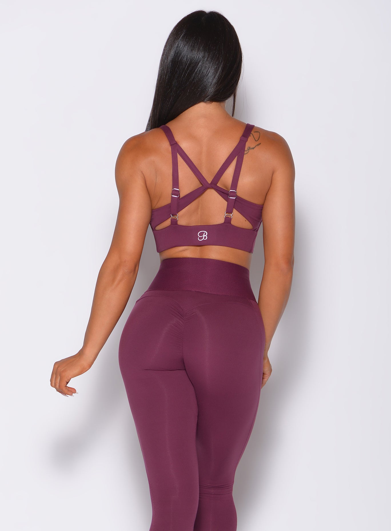 Back profile view of a model wearing our impact sports bra in majestic purple color and a matching leggings
