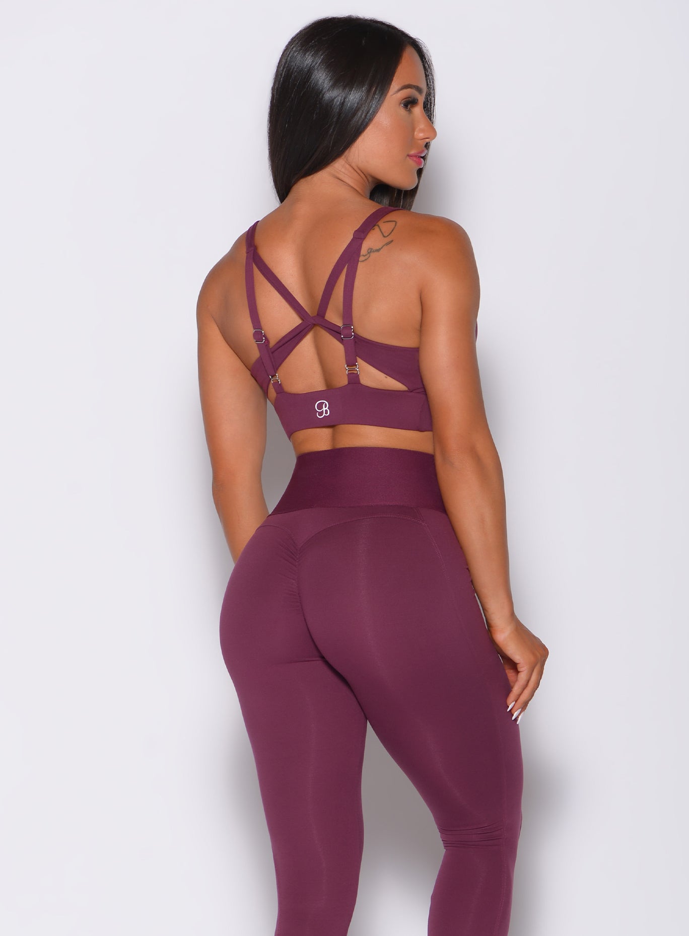 Back profile view of a model in our impact sports bra in majestic purple color and a matching high waist leggings