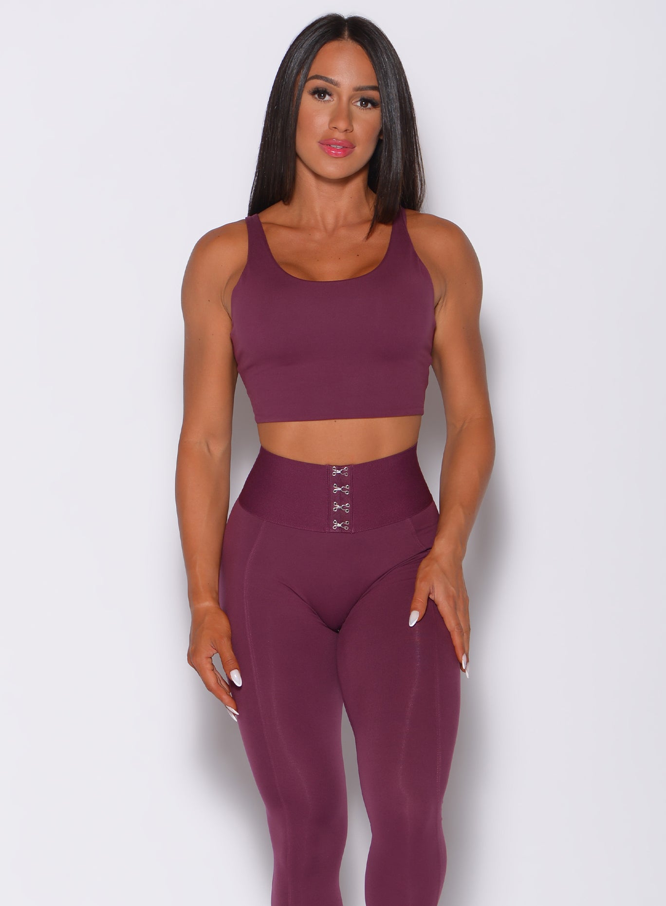 Front profile view of a model wearing our impact sports bra in majestic purple color and a matching leggings