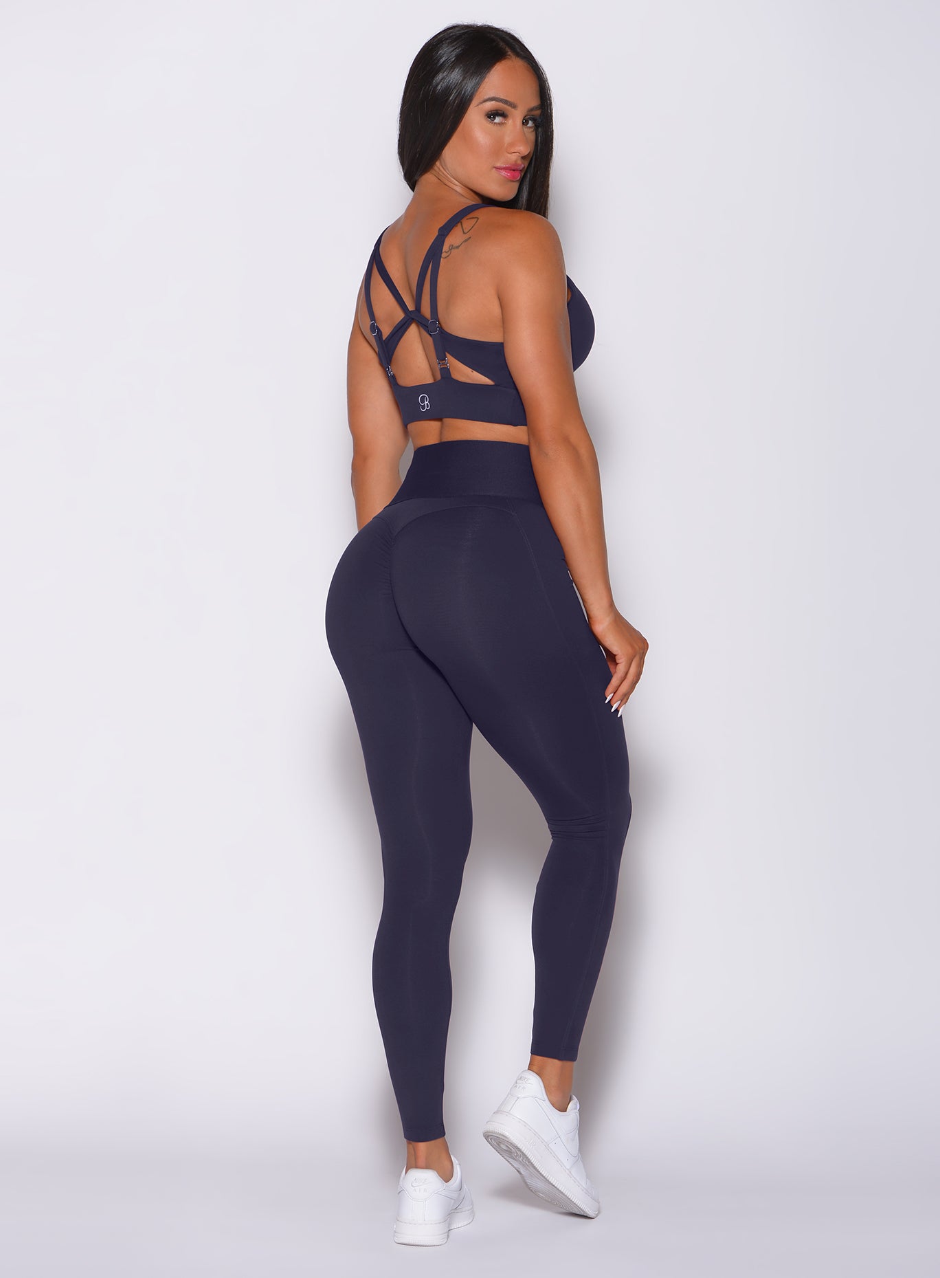 Right side profile view of a model in our waist cincher leggings in twilight blue color and a matching bra