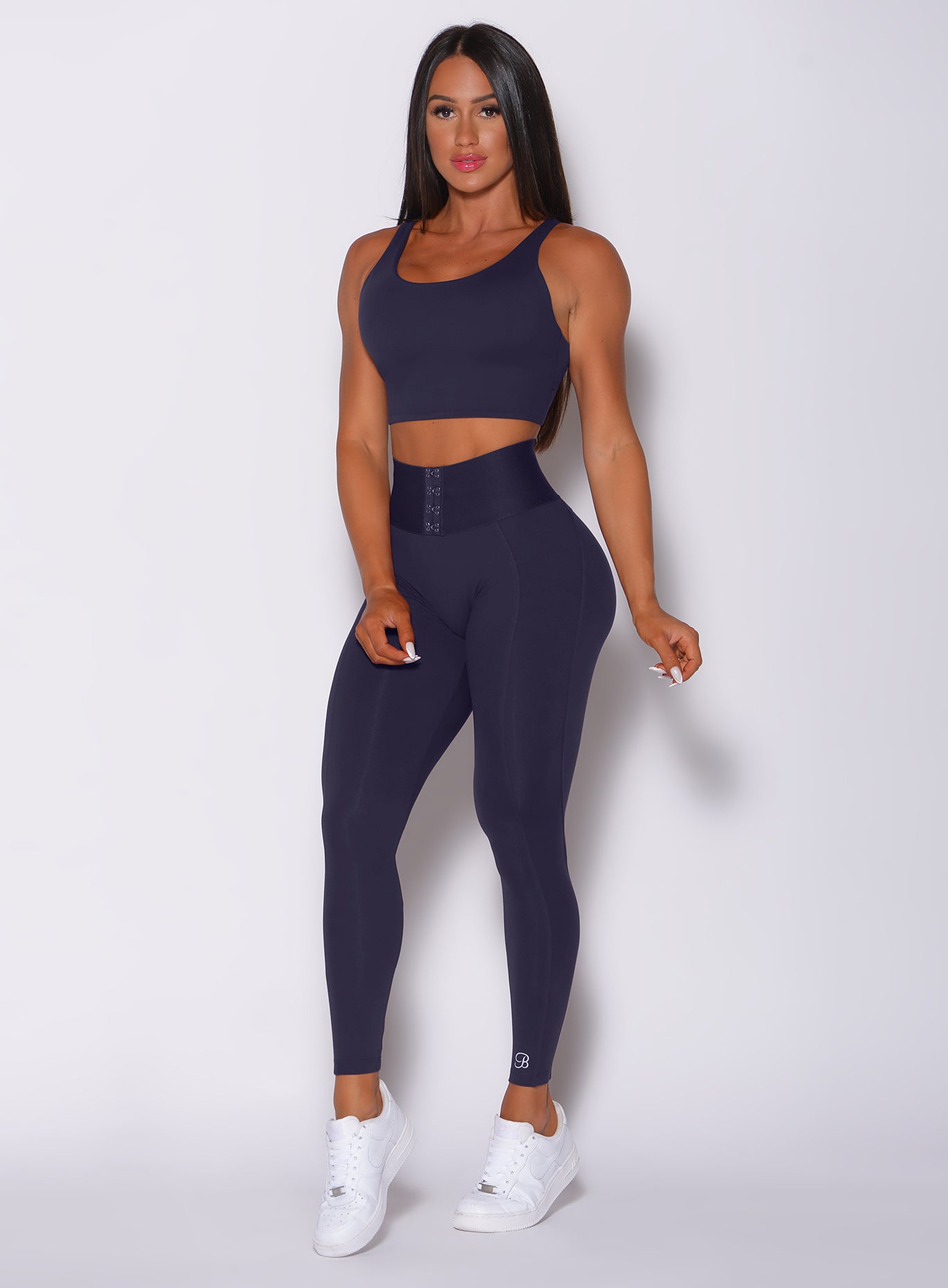 Front profile view of a model in our waist cincher leggings in twilight blue color and a matching bra