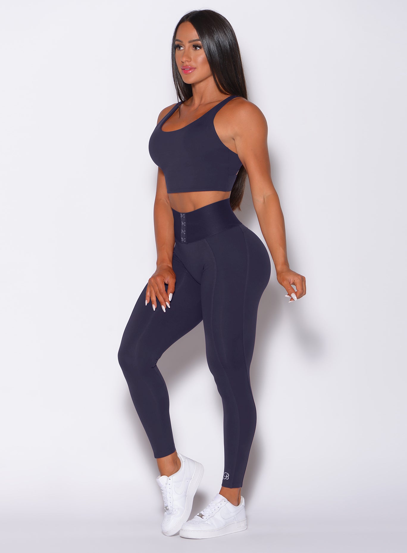 Left side profile view of a model in our waist cincher leggings in twilight blue color and a matching bra