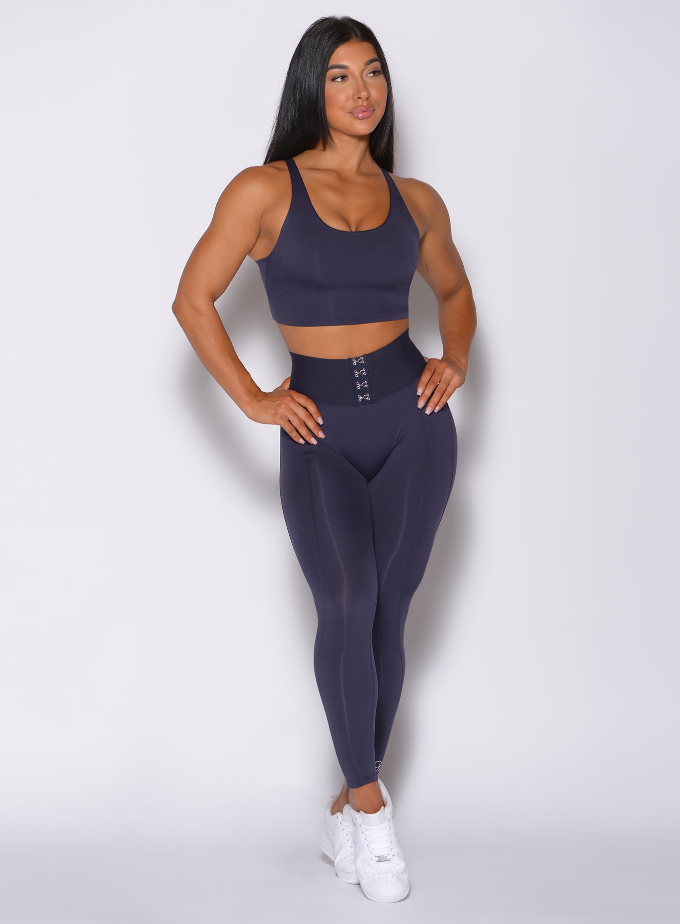 Front profile view of a model wearing our waist cincher leggings in twilight blue color and a matching bra