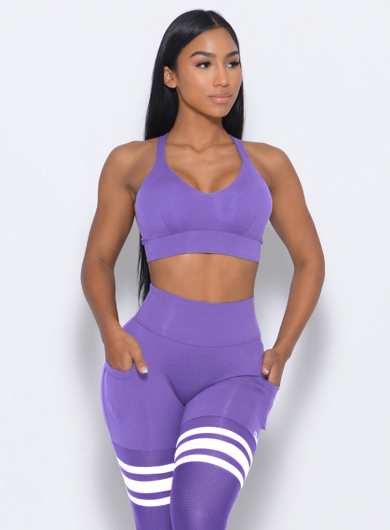 Front profile view of the model in our synergy sports bra in royal purple color and a matching high waist leggings