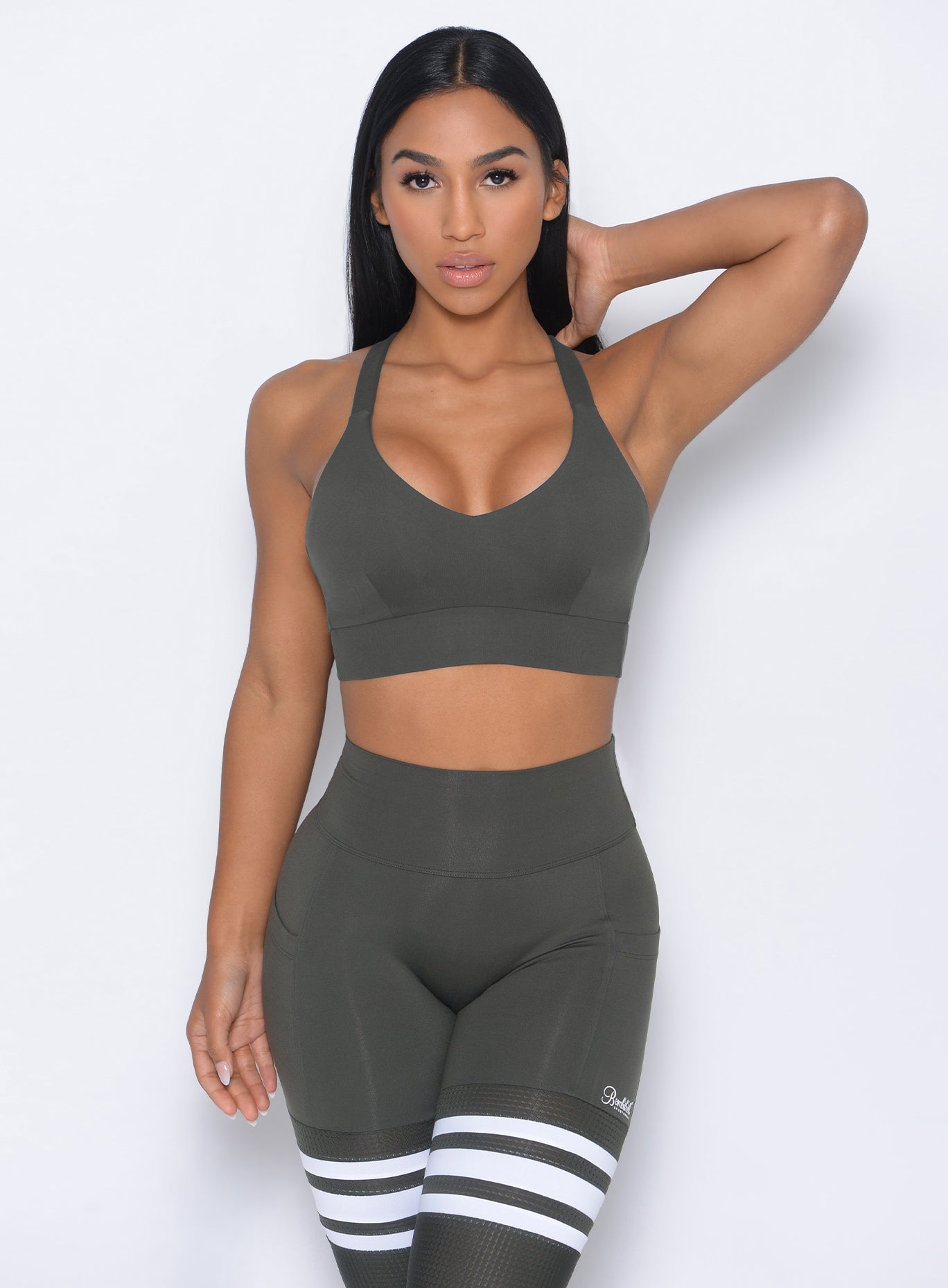 Model facing forward wearing our synergy sports bra in hunter green color and a matching leggings