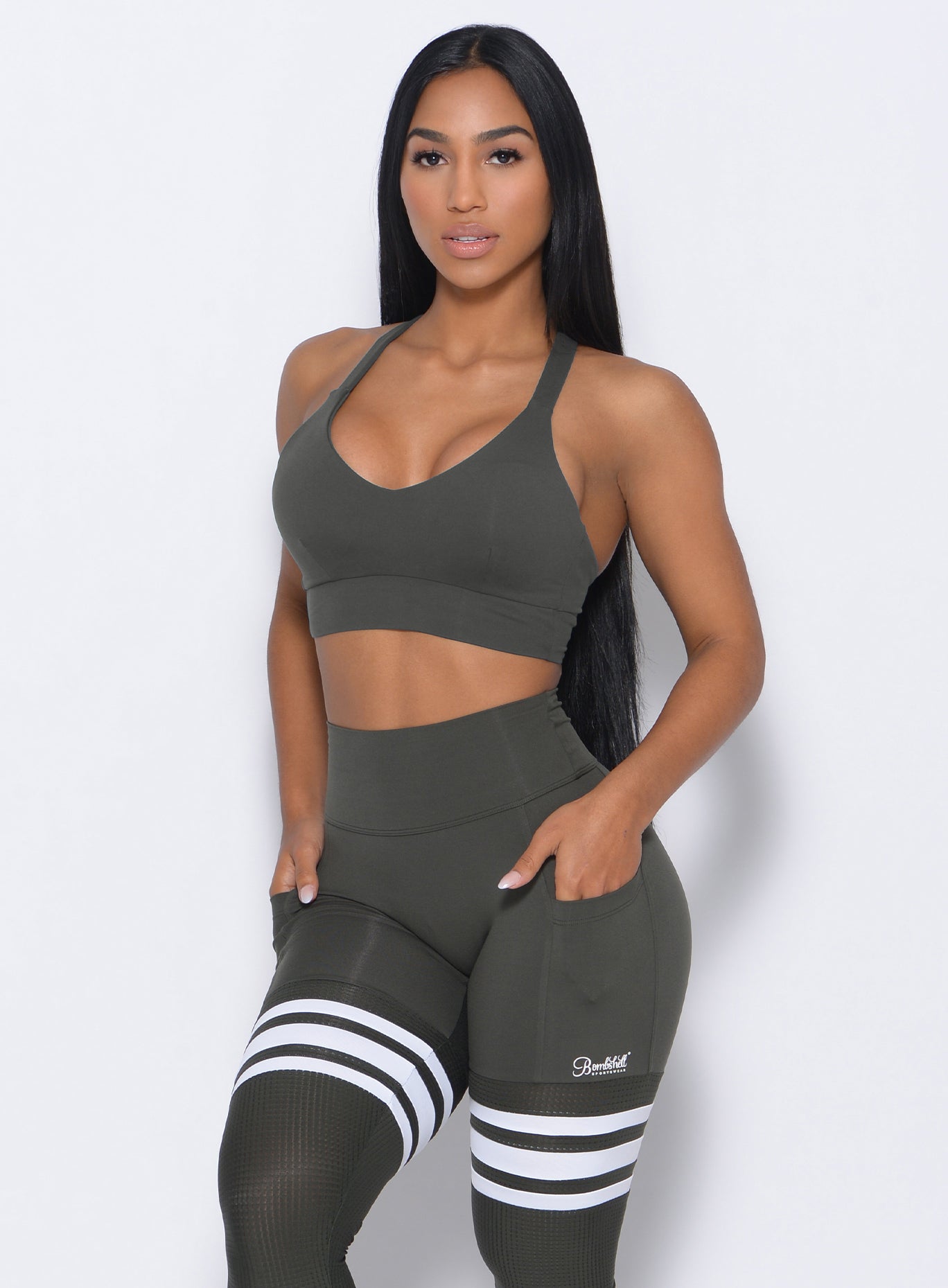 Front profile view of the model in our synergy sports bra in hunter green color and a matching leggings