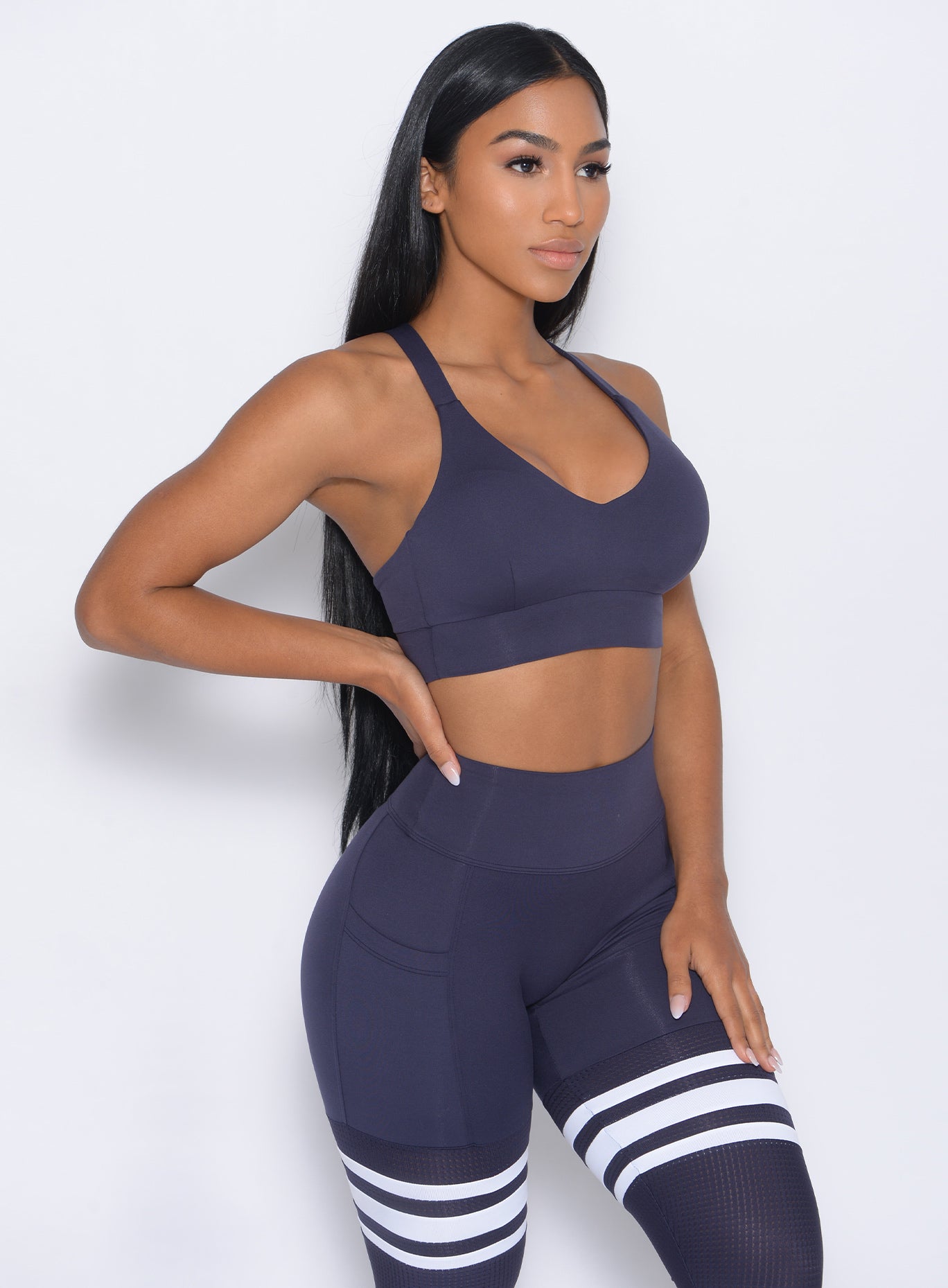 Right side view of the model angled right in our synergy sports bra in twilight blue color and a matching leggings