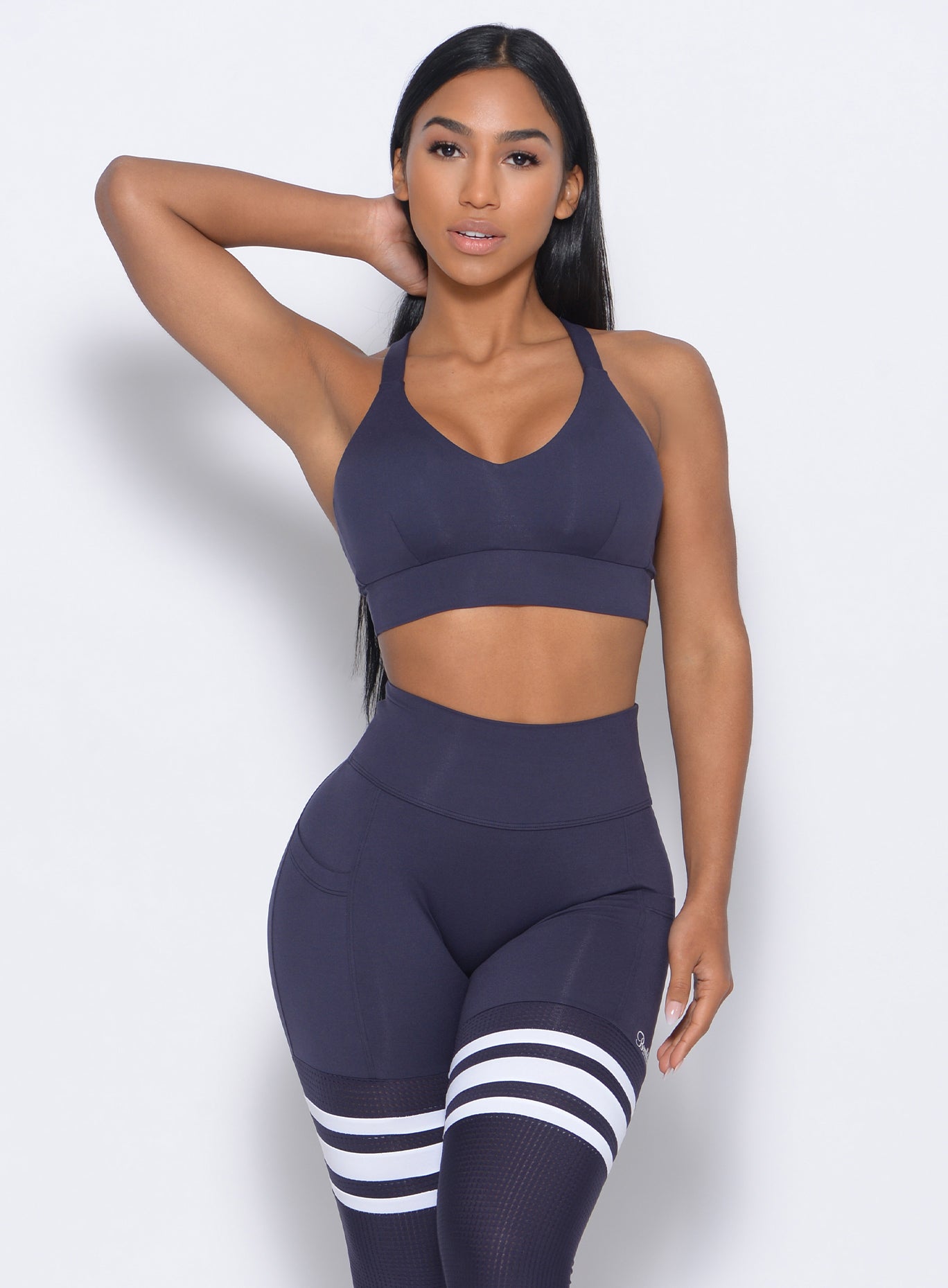 Front profile view of the model in our synergy sports bra in twilight blue color and a matching leggings 