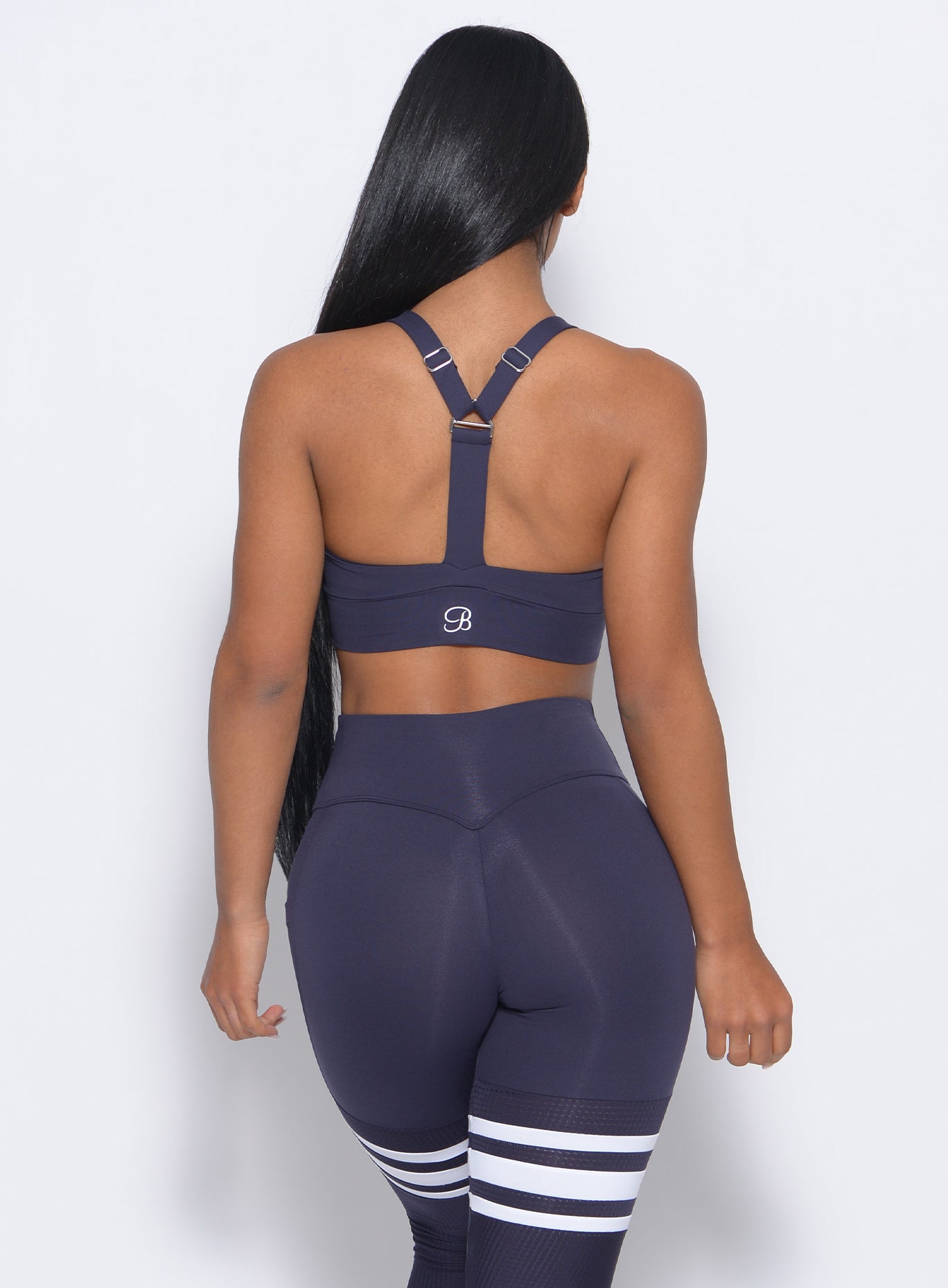 Back view of the model in our synergy sports bra in twilight blue color and a matching leggings