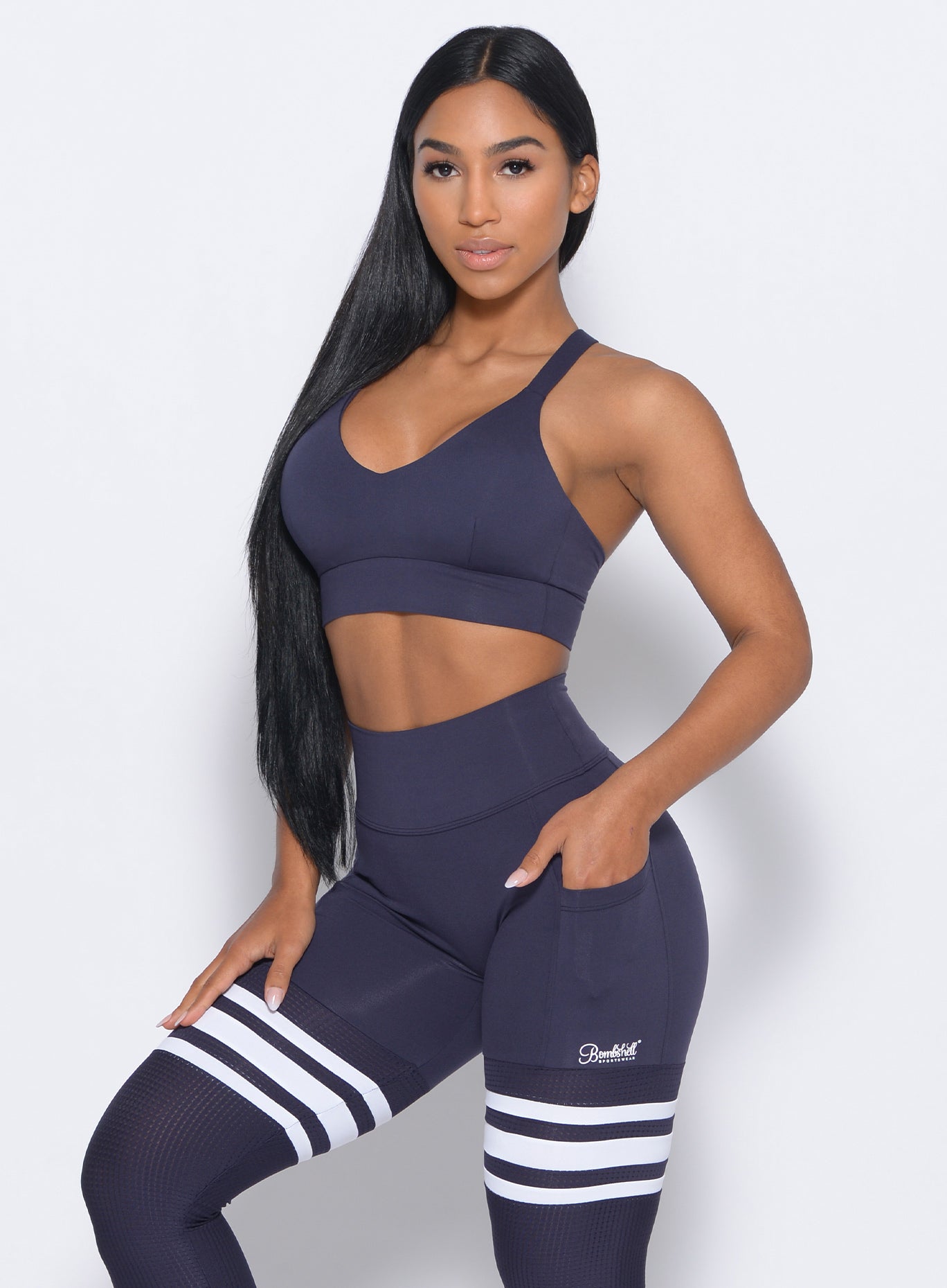 Left side view of the model angled left wearing our synergy sports bra in twilight blue color and a matching leggings