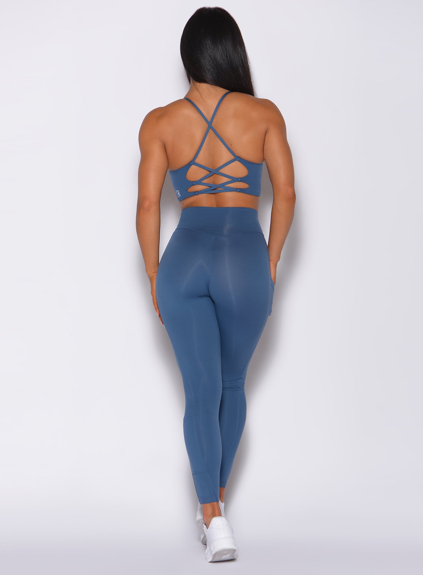 Back profile view of a model in our empower leggings in cool water color and a matching bra