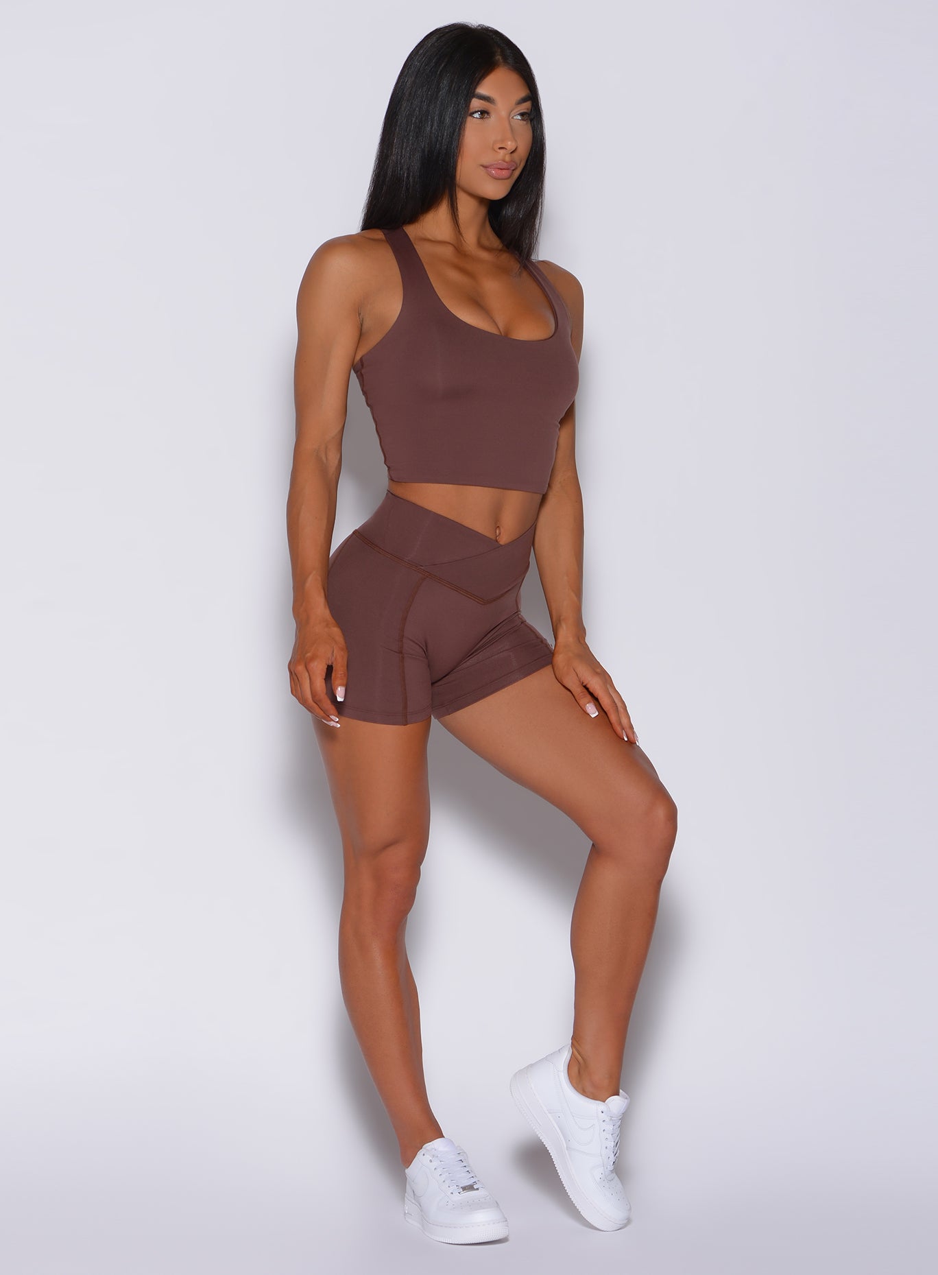 Right side profile view of a model angled right wearing our tiny waist shorts in chocolate color and a matching bra