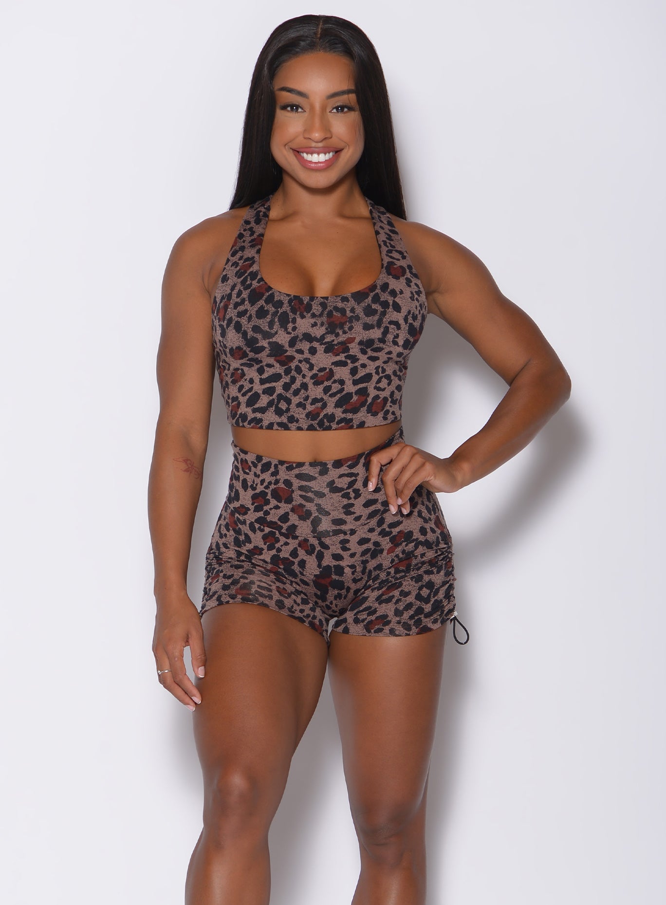 Front profile view of a model with her left hand on waist wearing our  toggle shorts in brown leopard print and a matching bra