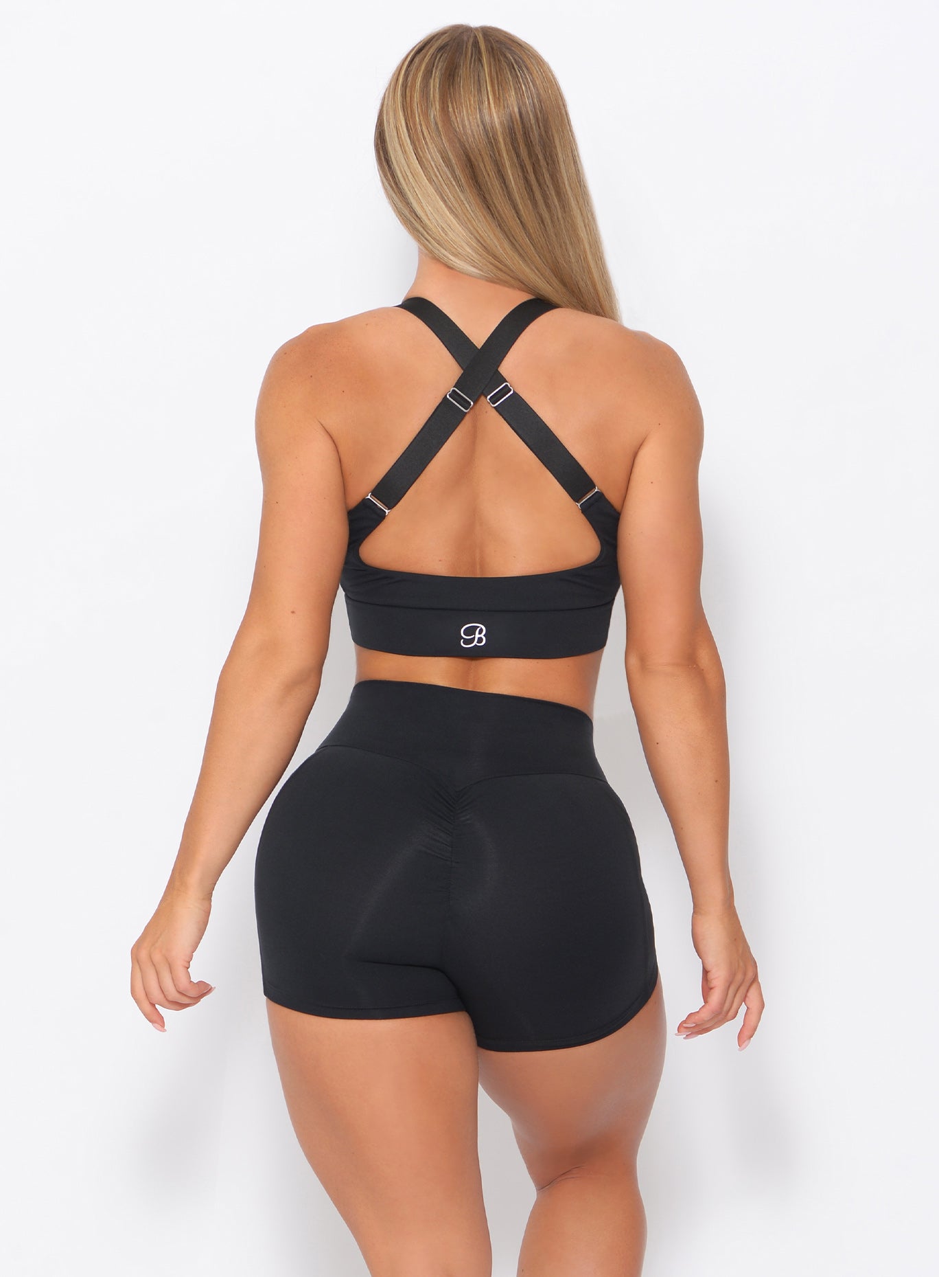 Back view of the model in our twisted sports bra in black color and a matching shorts  