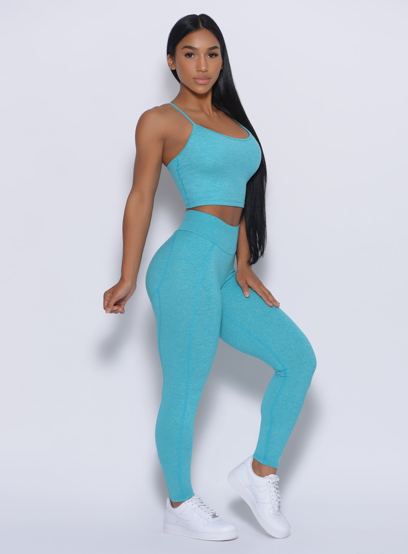 Right side view of a model angled right  wearing our uplift leggings in crystal blue color and a matching bra