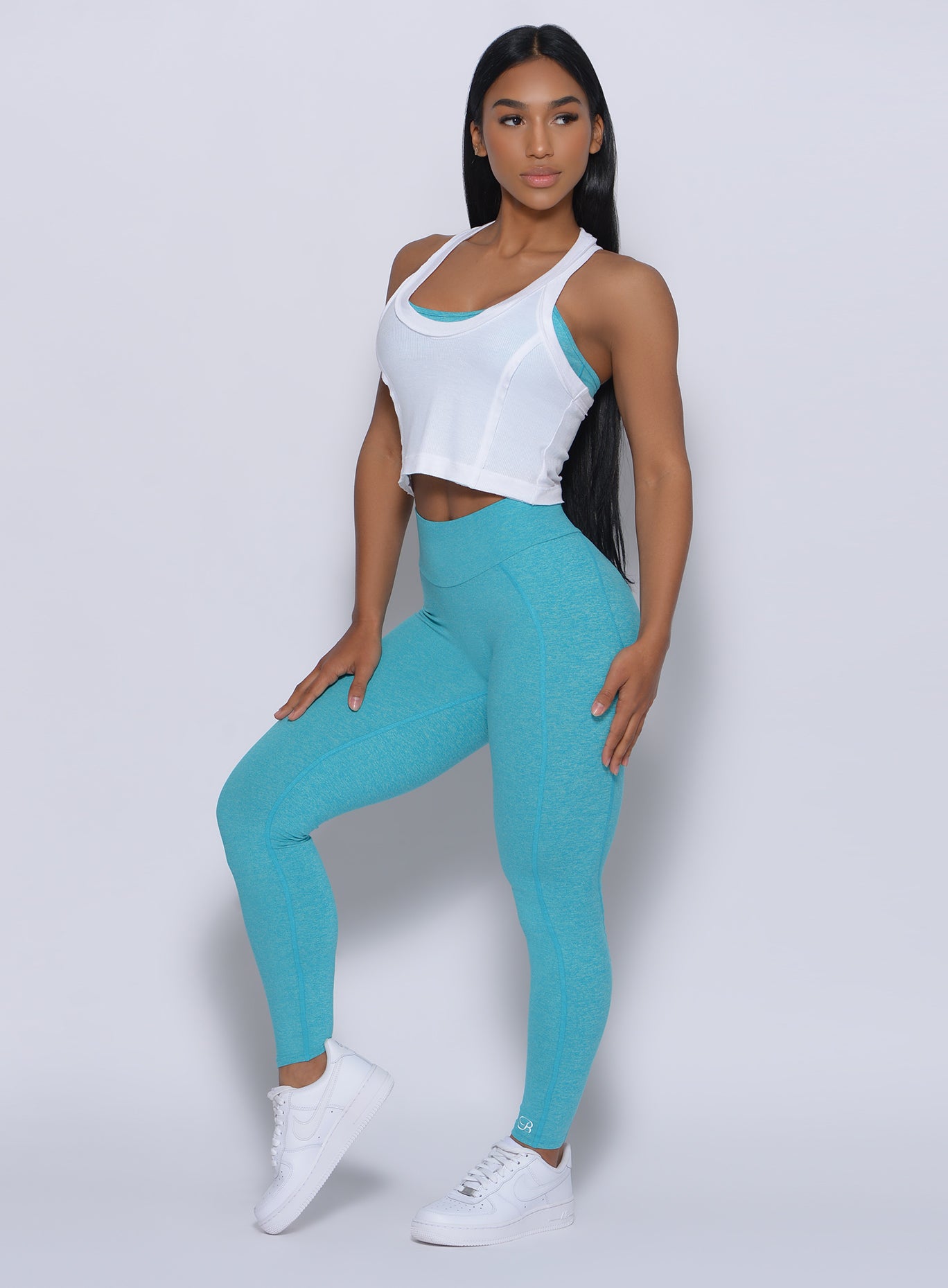 Right side view of a model angled right  wearing our white rib crop tank and a blue leggings