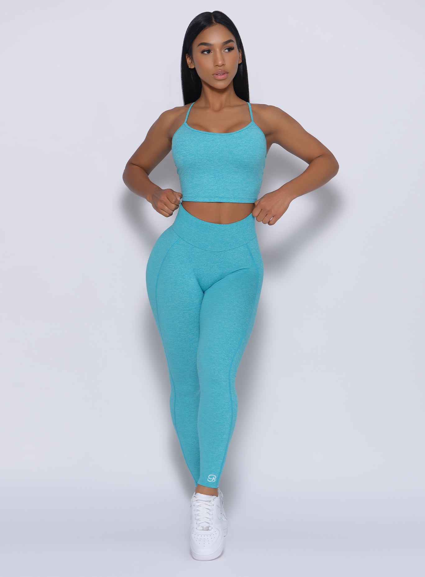 Front profile view of a model in our uplift leggings in crystal blue color and a matching bra 