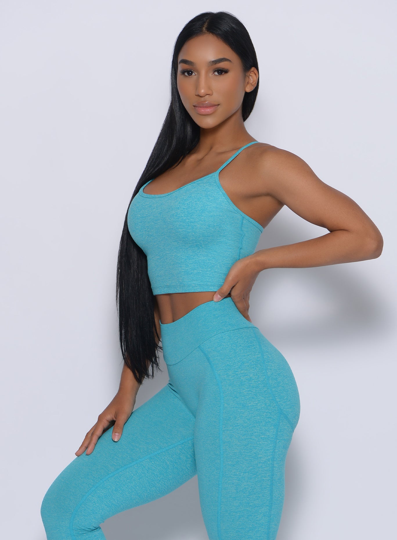 Right side view of a model angled right wearing our relax sports bra in crystal blue color and a matching leggings