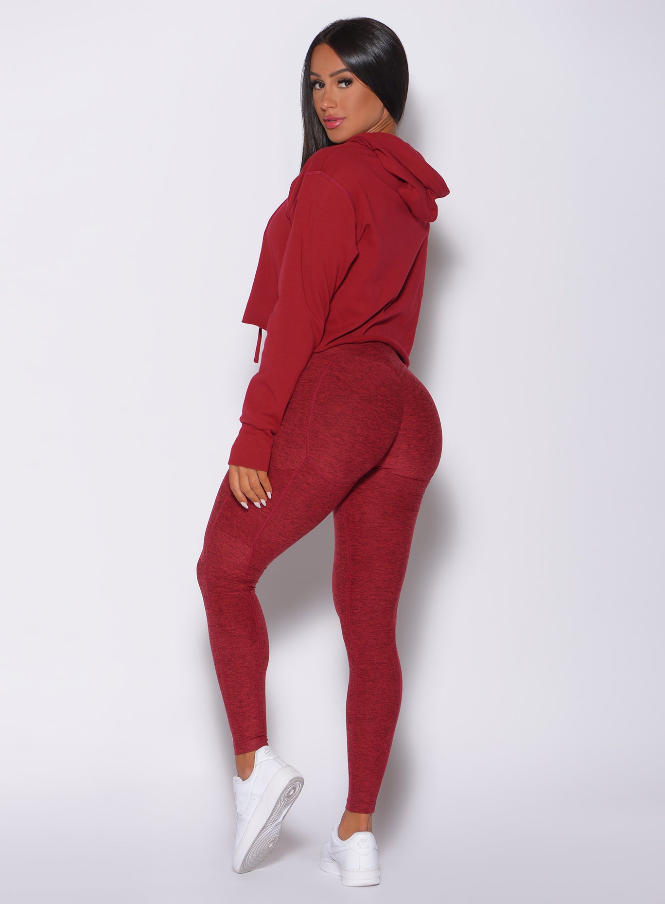 Left side profile view of a model in our bombshell hoodie in red rose color and a matching high waist leggings