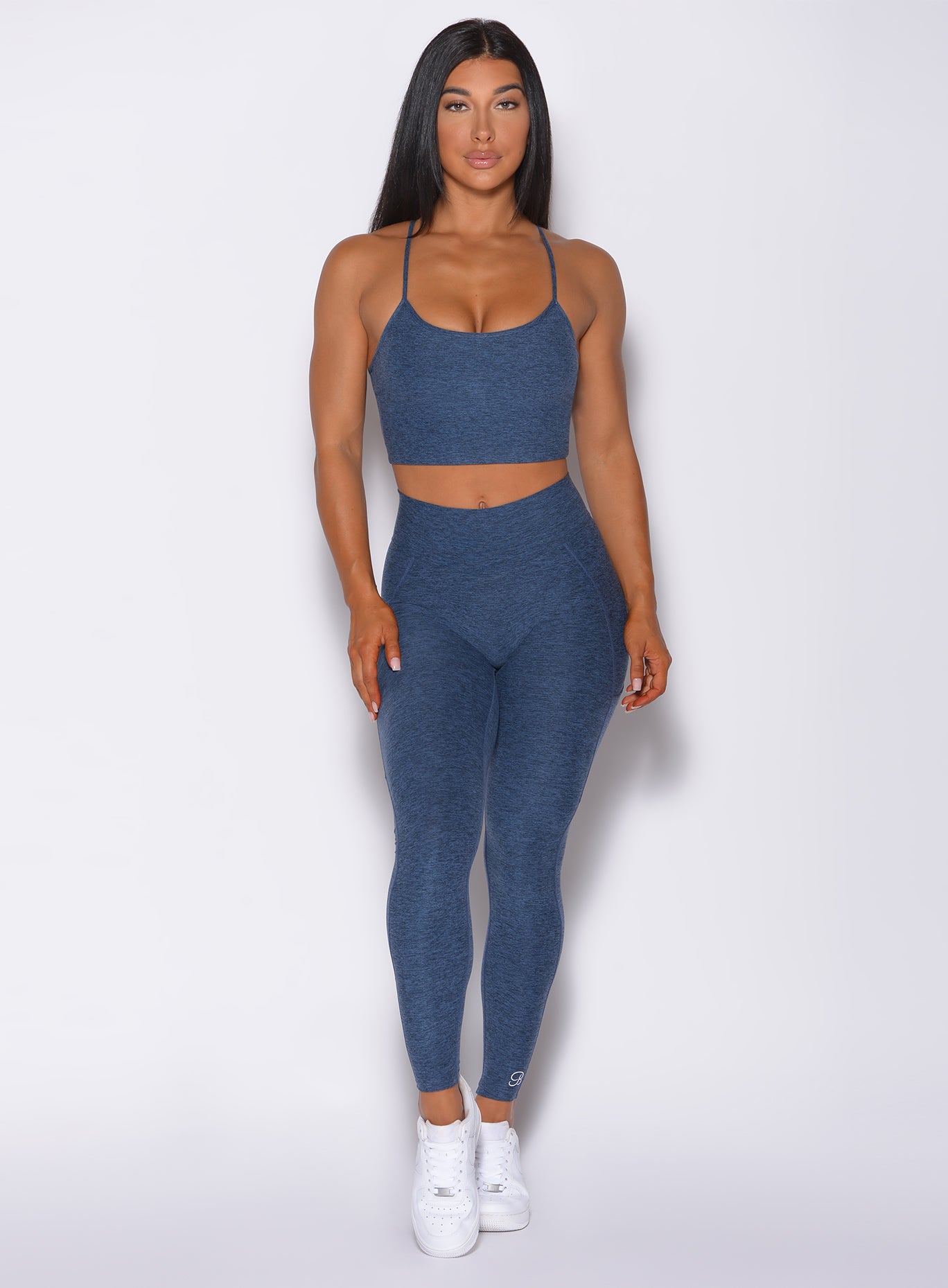 Front profile view of a model in our uplift pocket leggings in night sky color and a matching bra