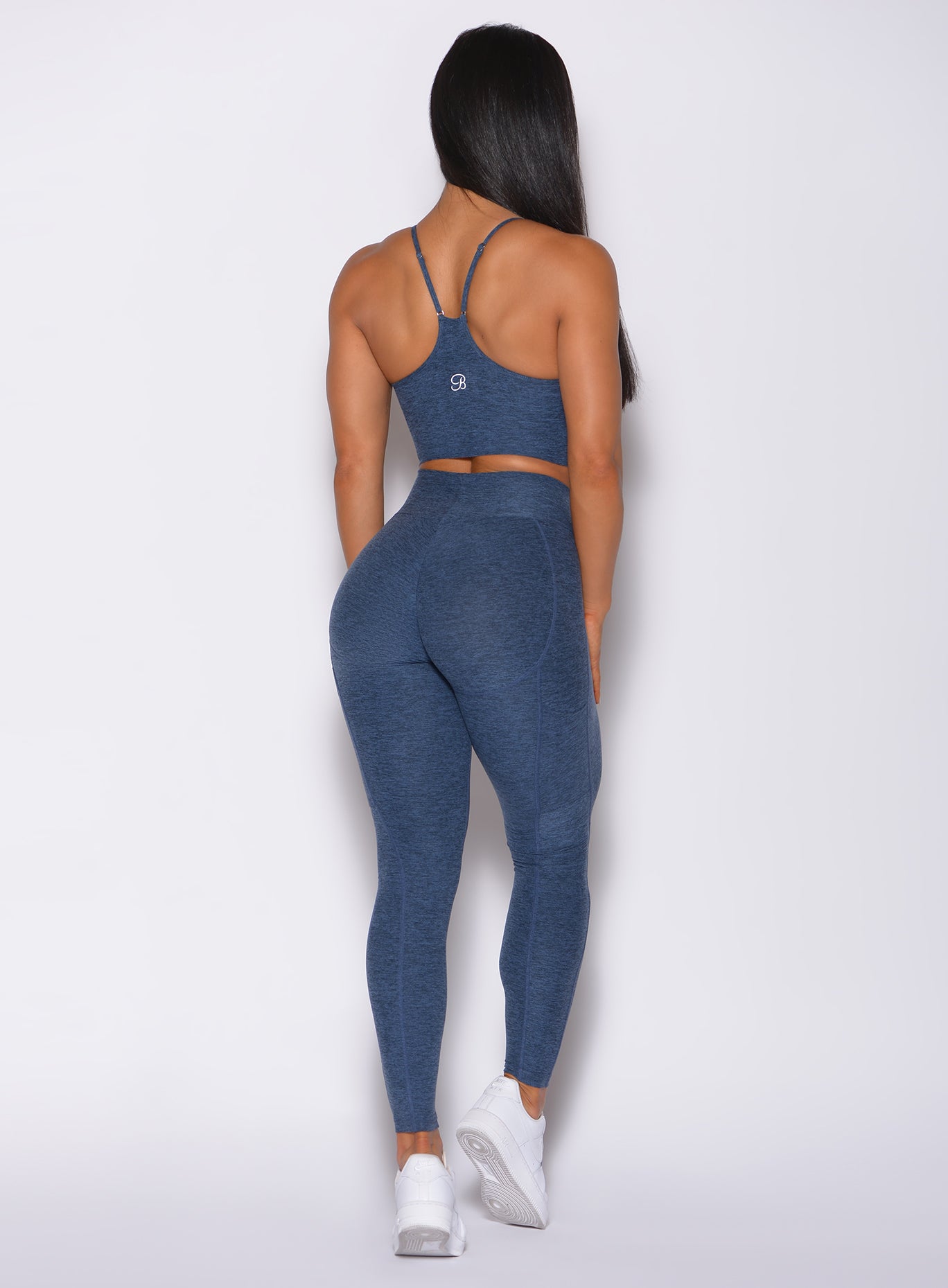 Back profile view of a model in our uplift pocket leggings in night sky color and a matching sports bra 