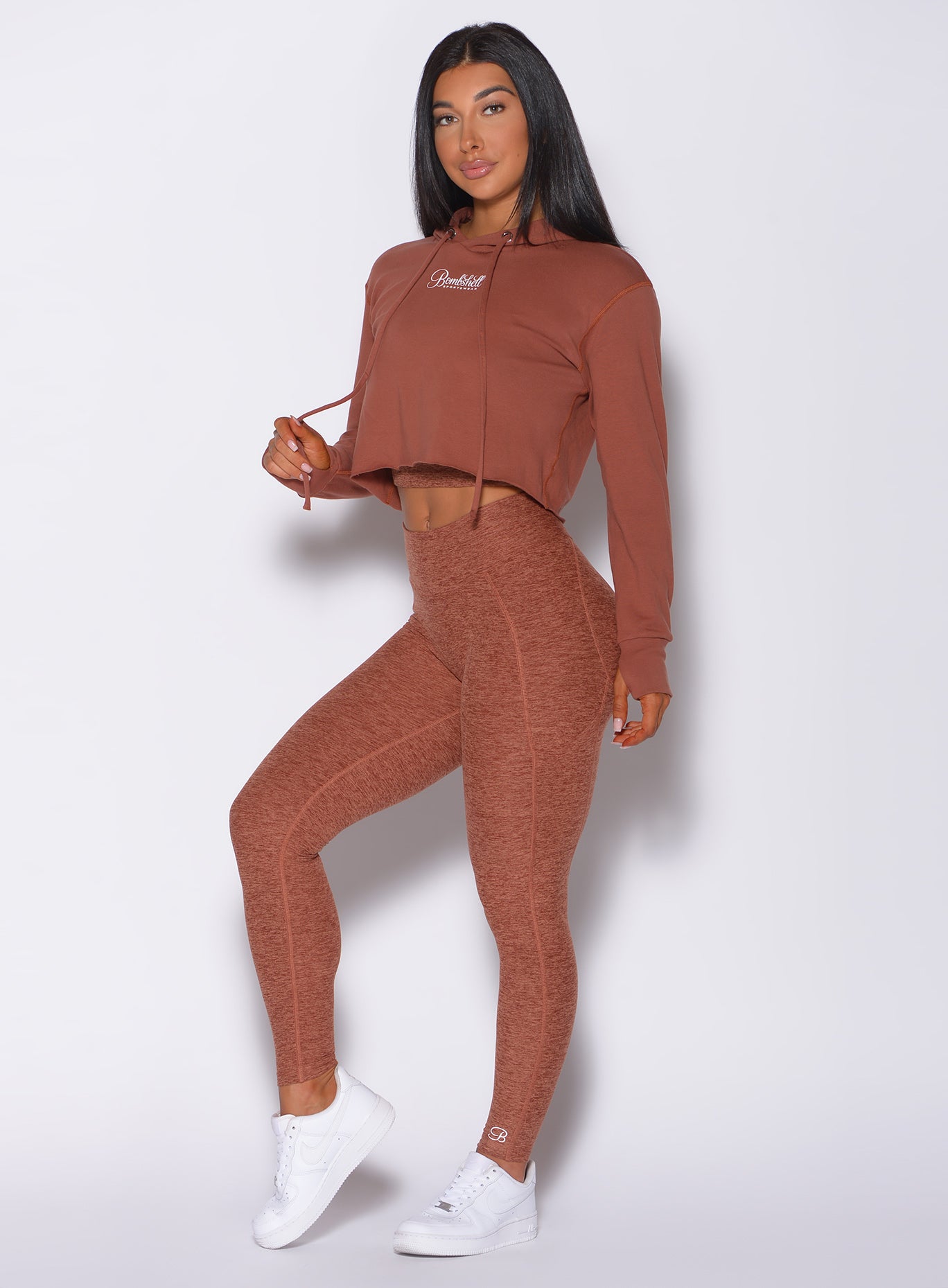 Front profile view of the model in our bombshell hoodie in caramel color and a matching high rise leggings