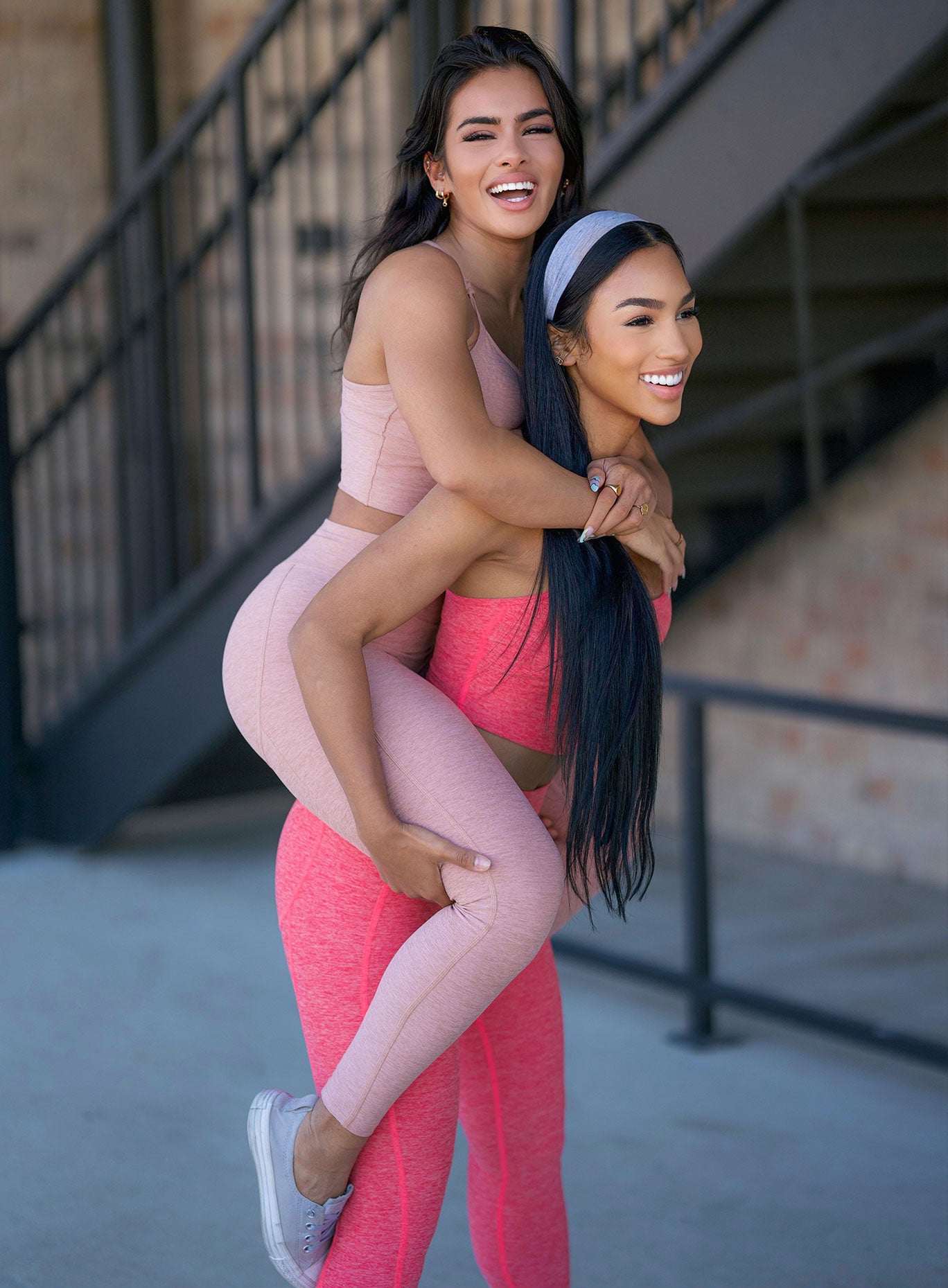 Picture of a model carrying another model on her back and wearing our uplift leggings in latte and papaya color along with the matching bras