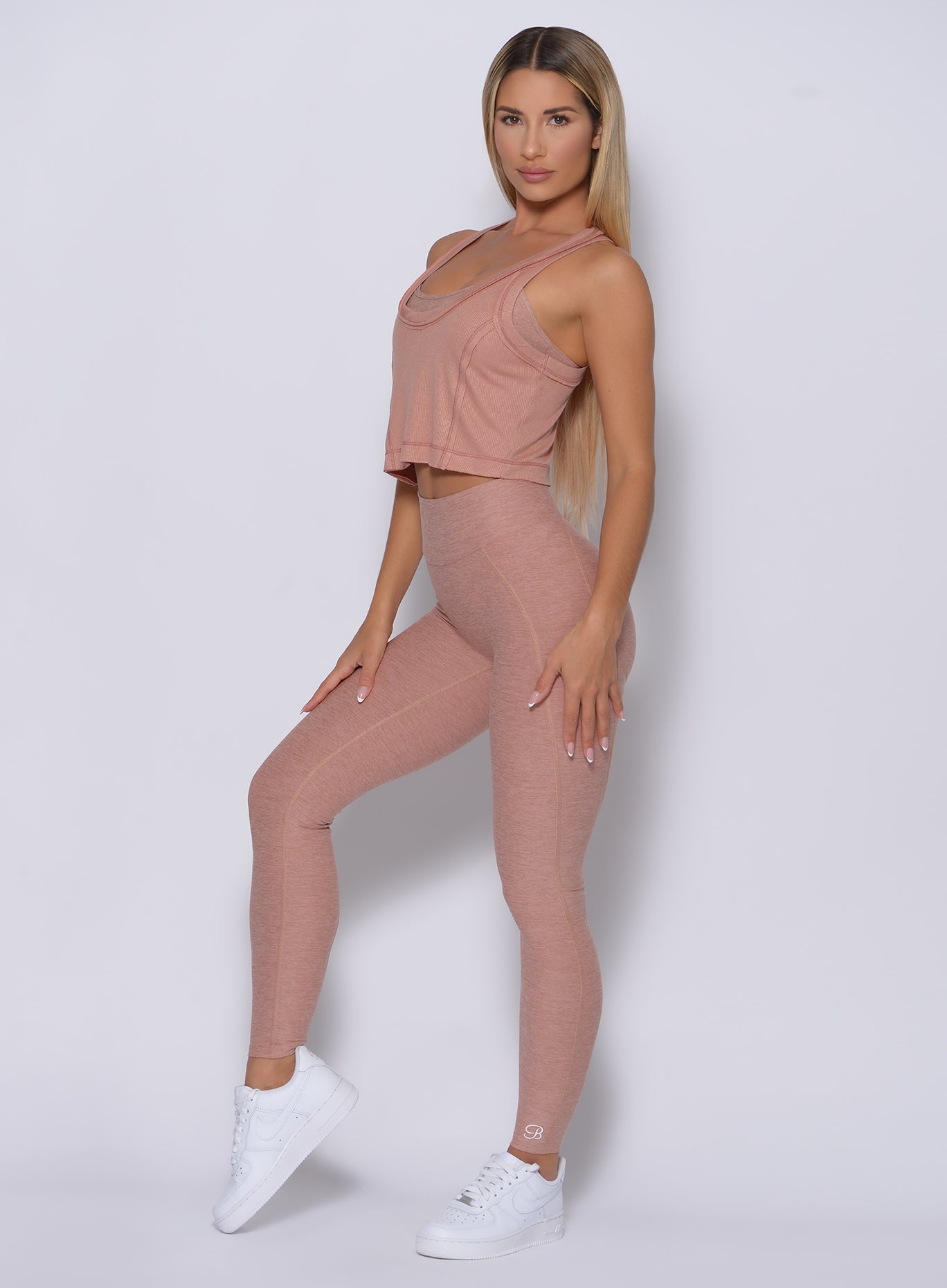 Left side profile view of a model angled left wearing our rib crop tank in frappe color and a matching leggings