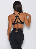 Back view of the model in a high waist black leggings with a V back design