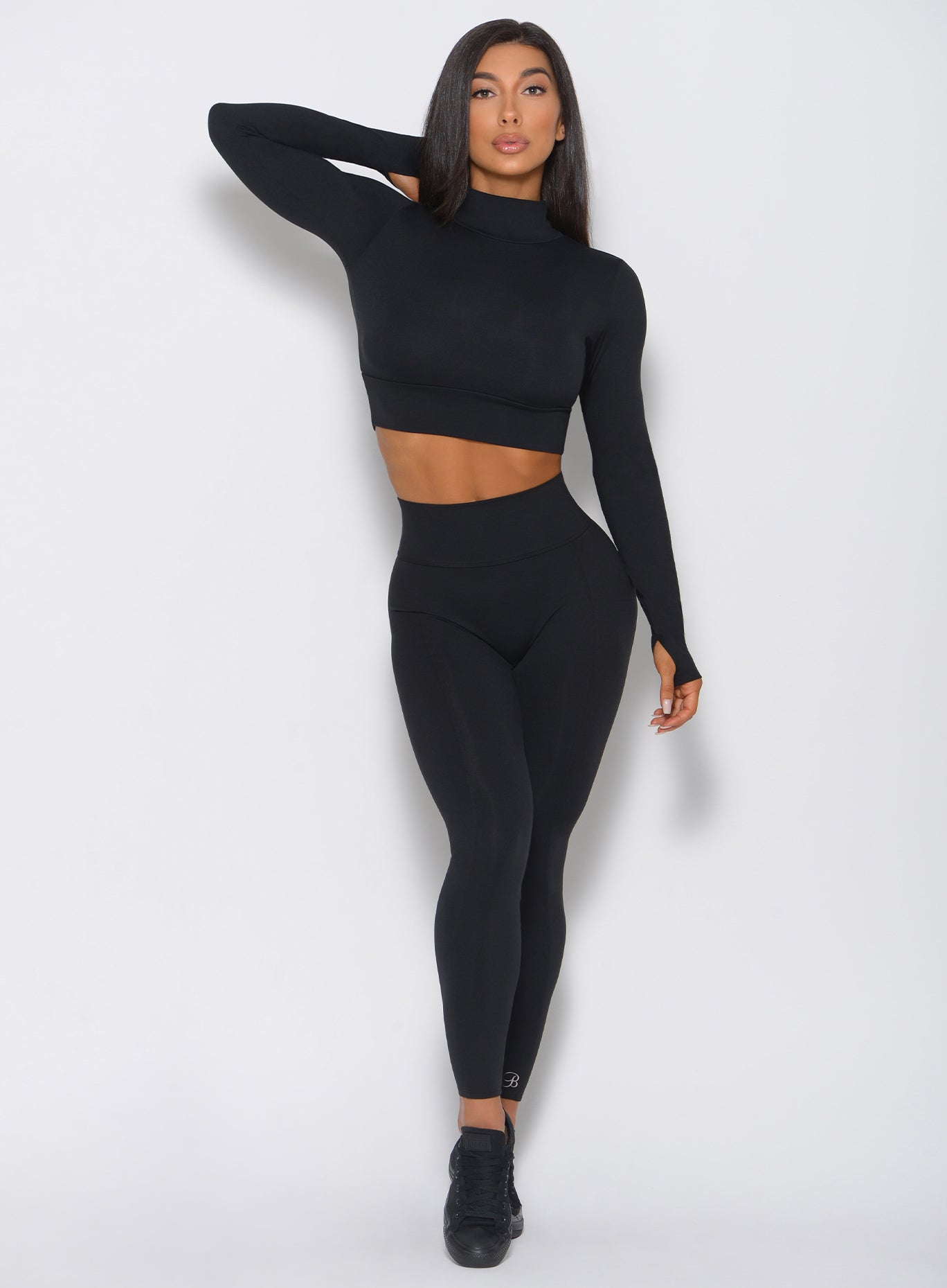 Front profile view of a model wearing our victory leggings in black along with a matching pullover 