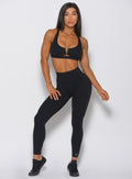 Picture of a model facing forward wearing our victory leggings in black and a matching bra 