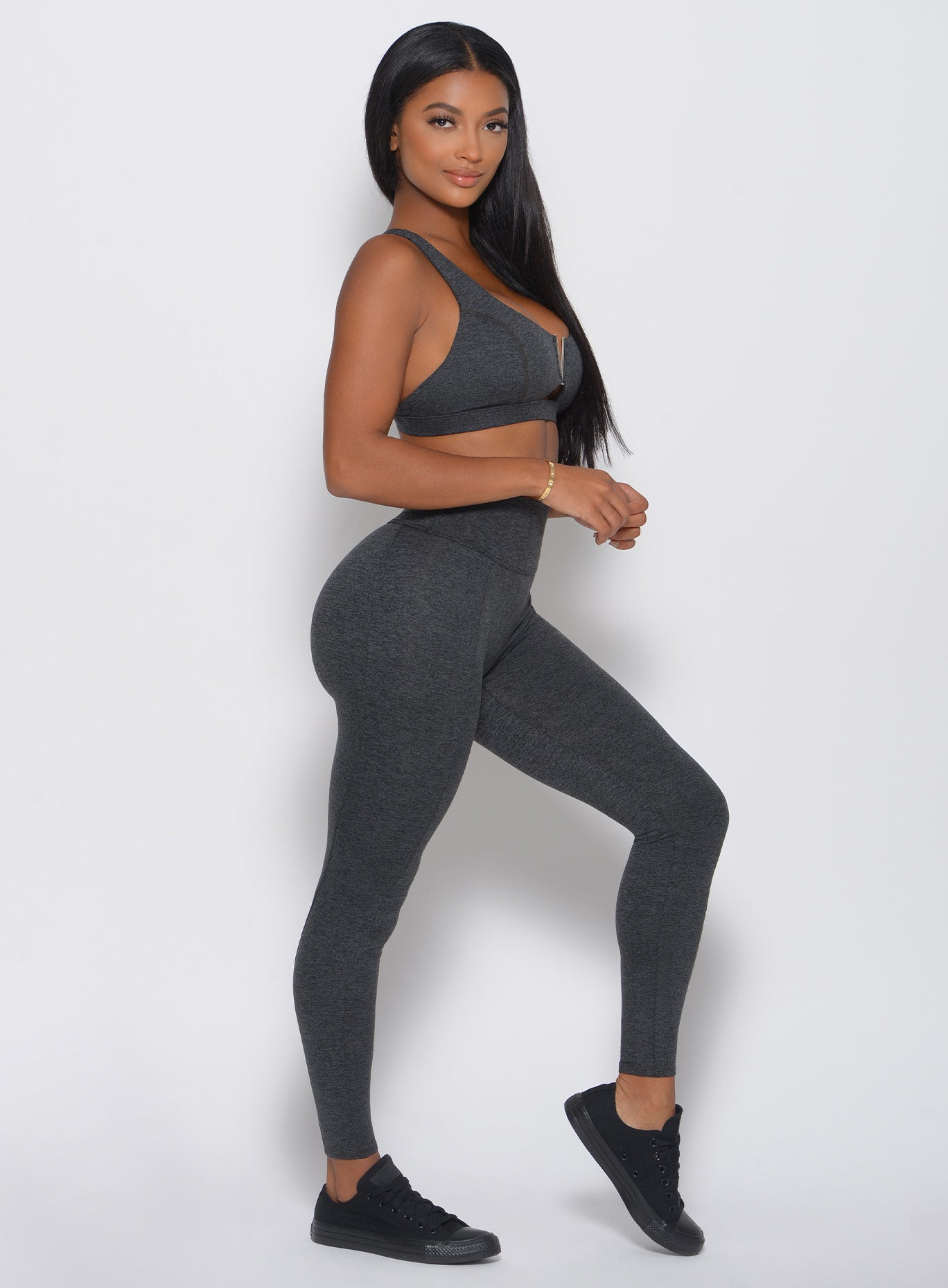 Left side view of the model in a high waist gray leggings with a V back design