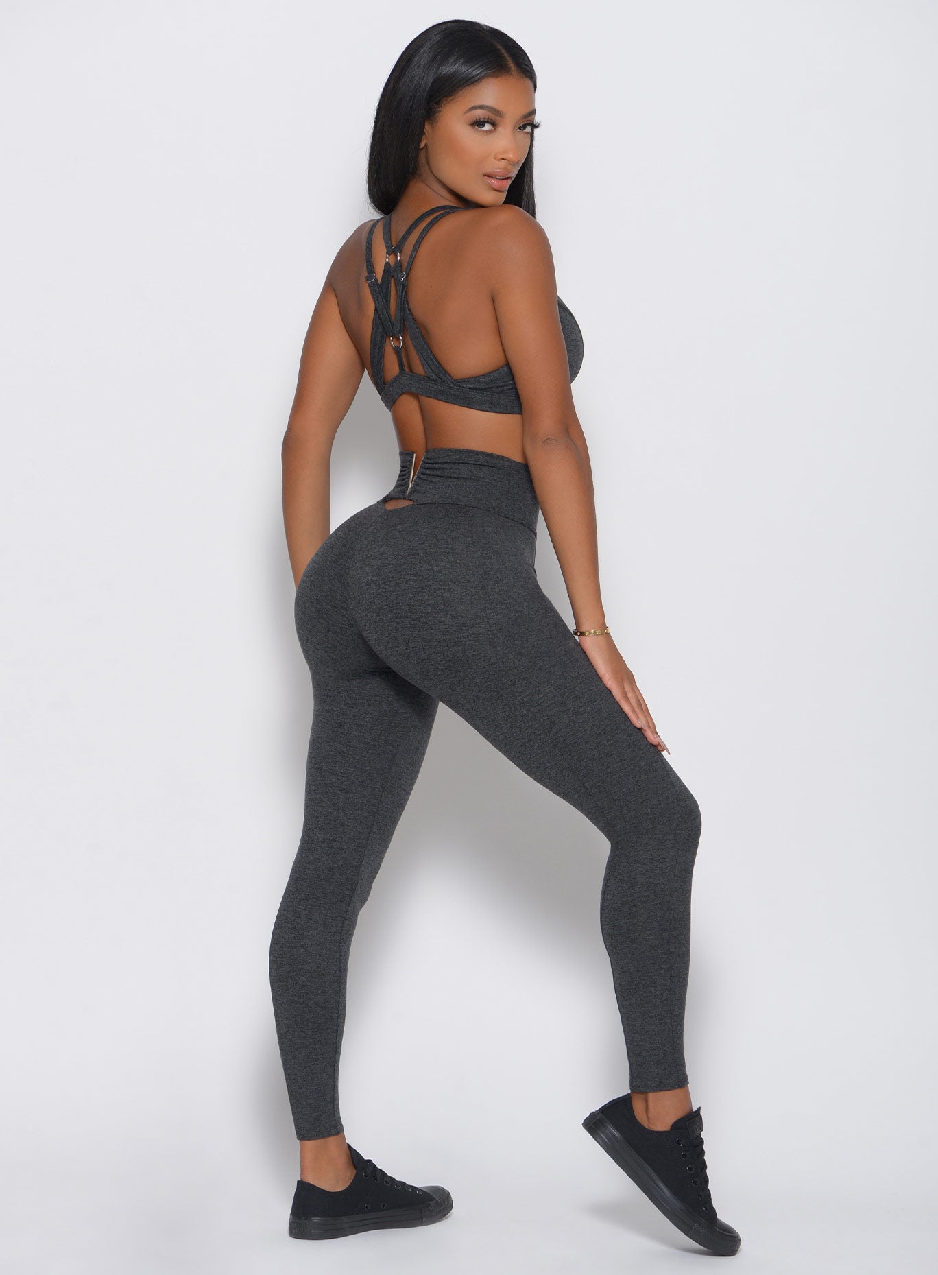 Back view of the model in a high waist gray leggings with a V back design