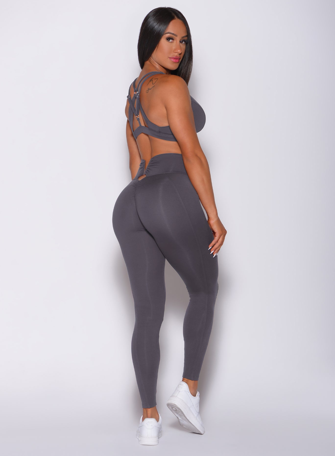 Right side profile view of a model facing to her right wearing our victory scrunch leggings in shadow color and a matching sports bra