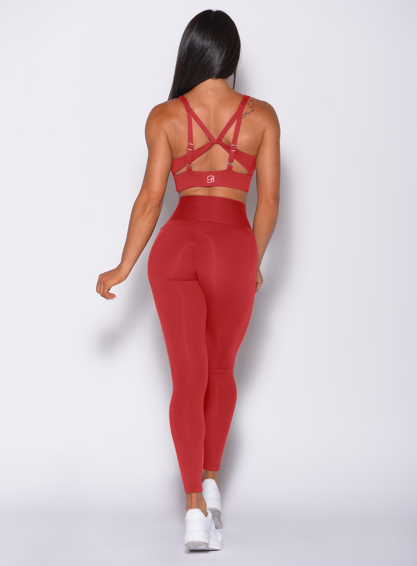 Back  profile view of a model wearing our waist cincher leggings in sunset red color and a matching bra
