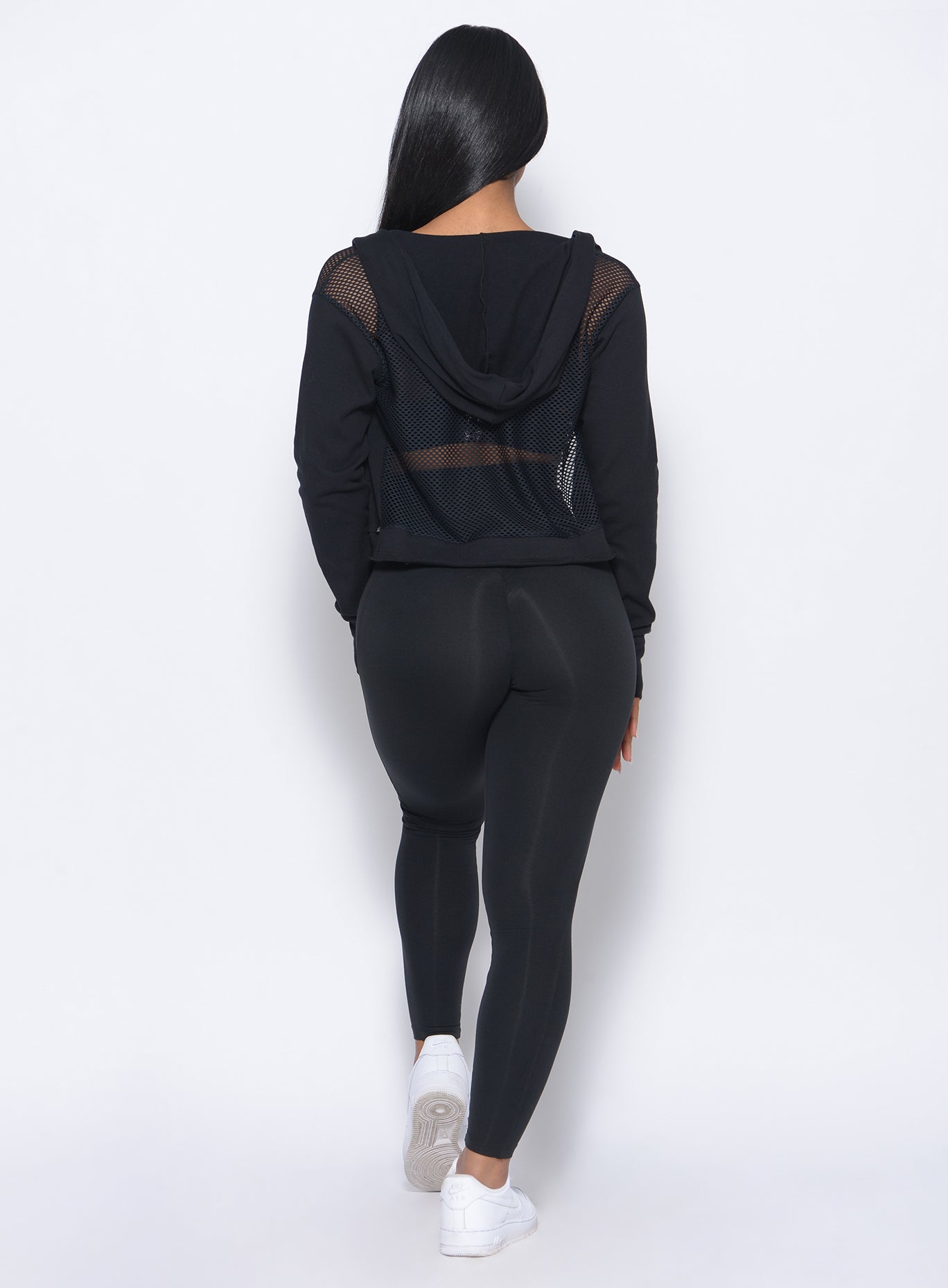 back profile of model wearing the waist cincher leggings in black and a matching jacket 