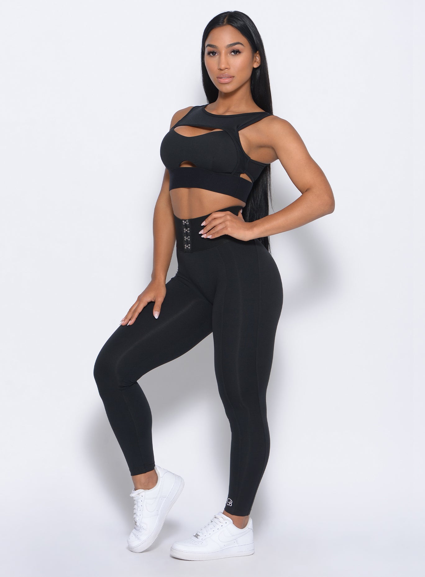 Left side view of the model angled left in our black waist cincher leggings and a matching bra