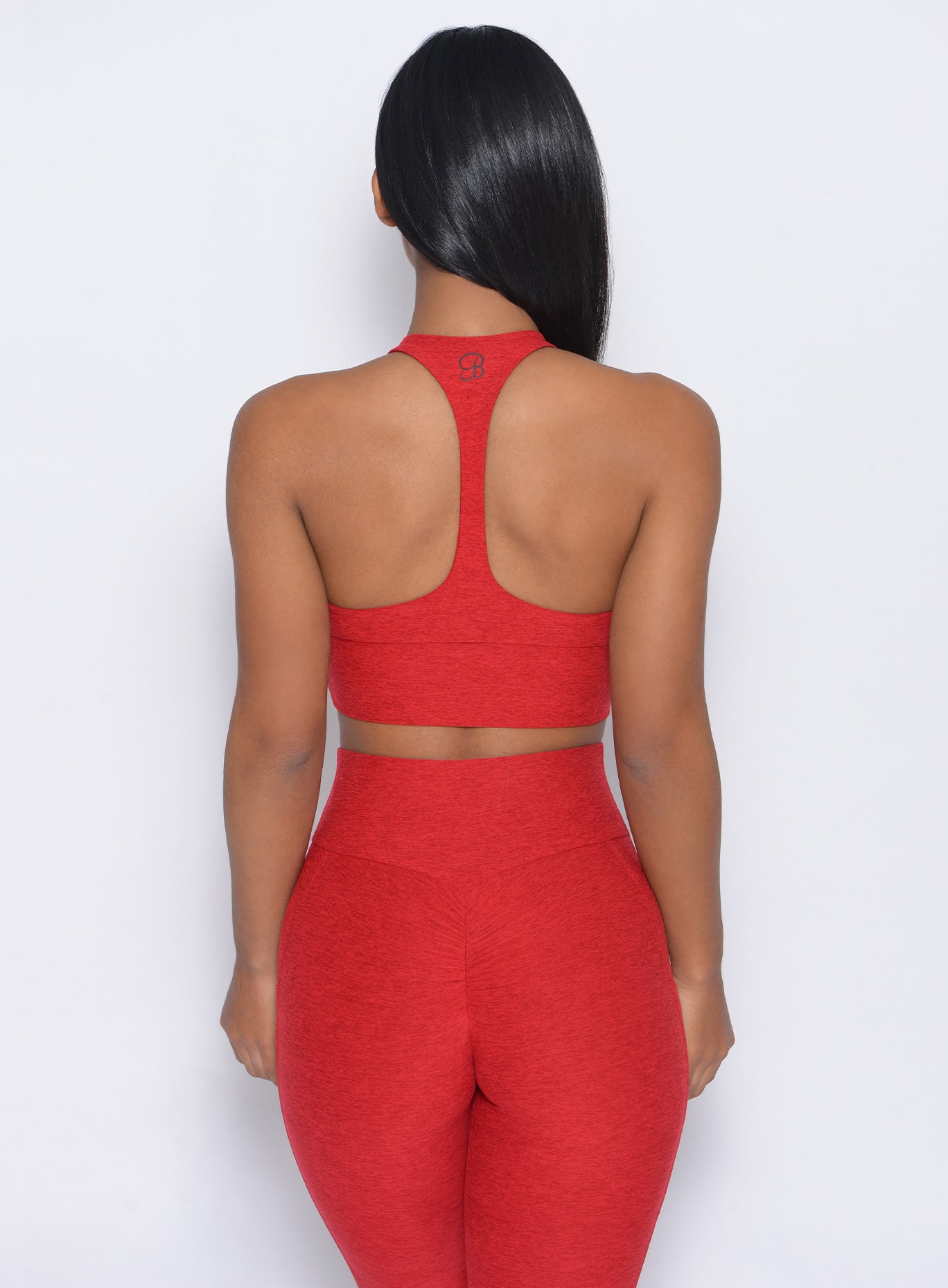 Back view of the model in our edgy longline bra in sunset red color and a matching leggings