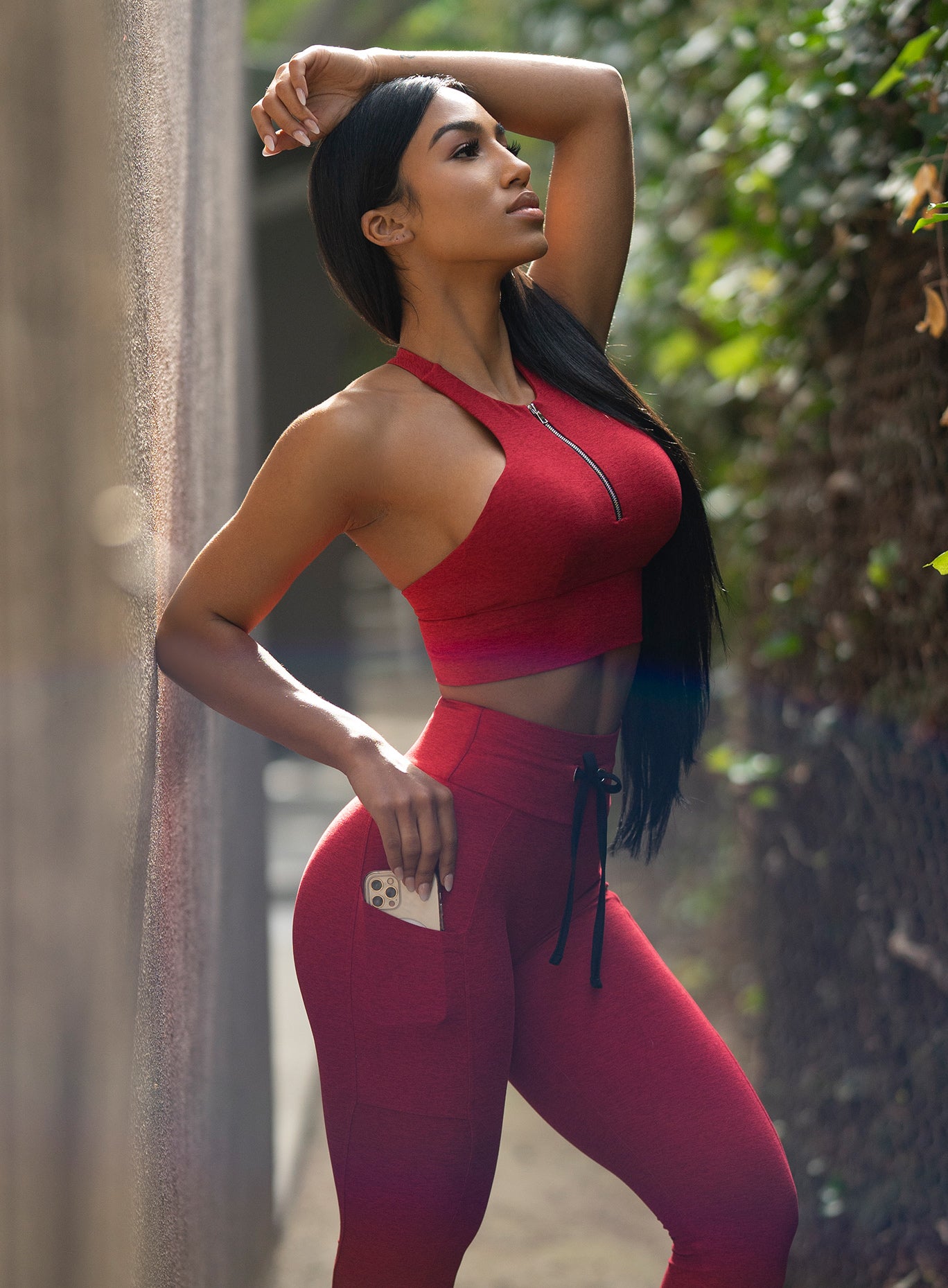 Right side view of the model wearing our edgy longline bra in sunset red color and a matching leggings