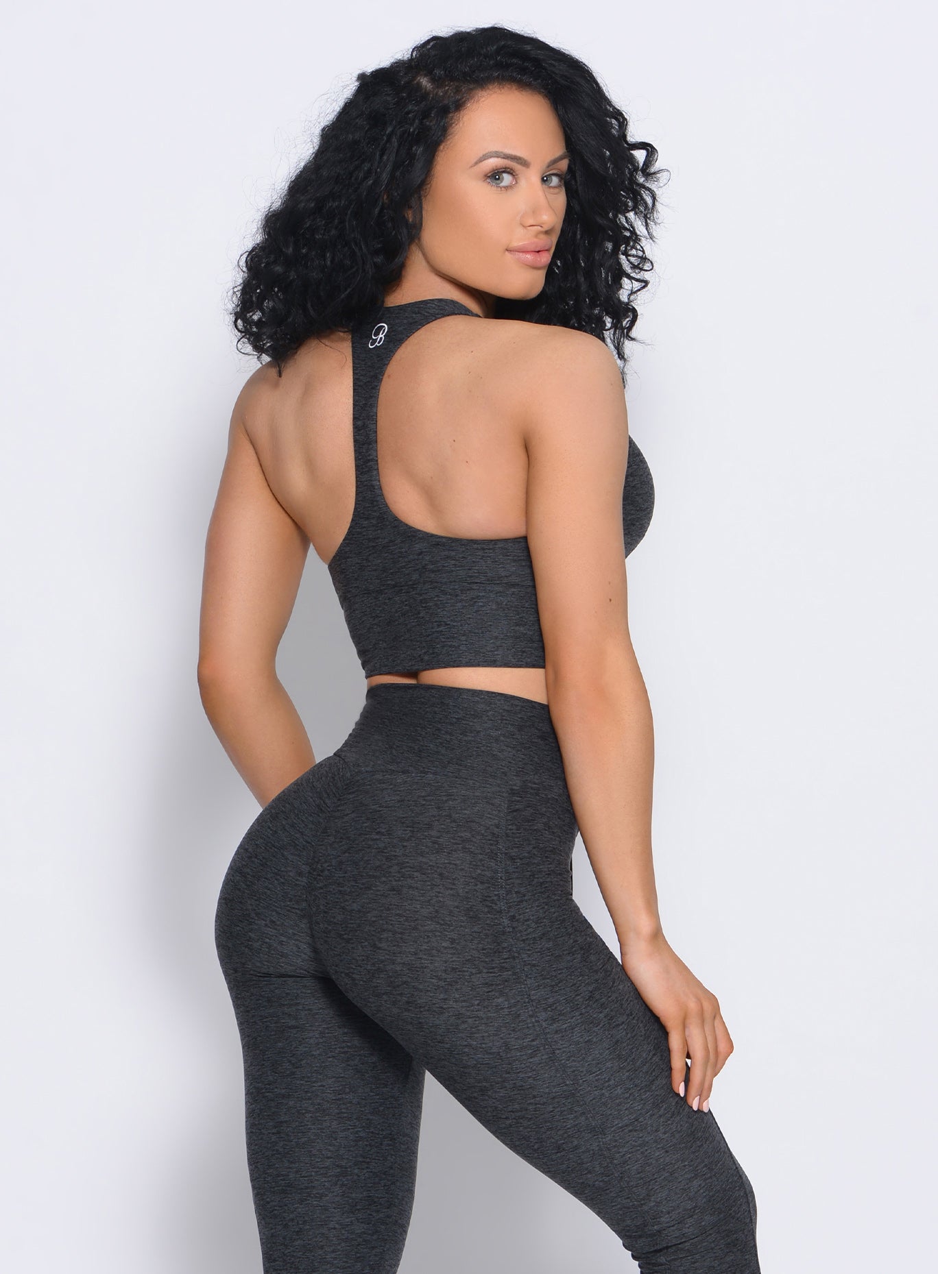 Back view of the model wearing our edgy longline bra in charcoal color and a matching leggings