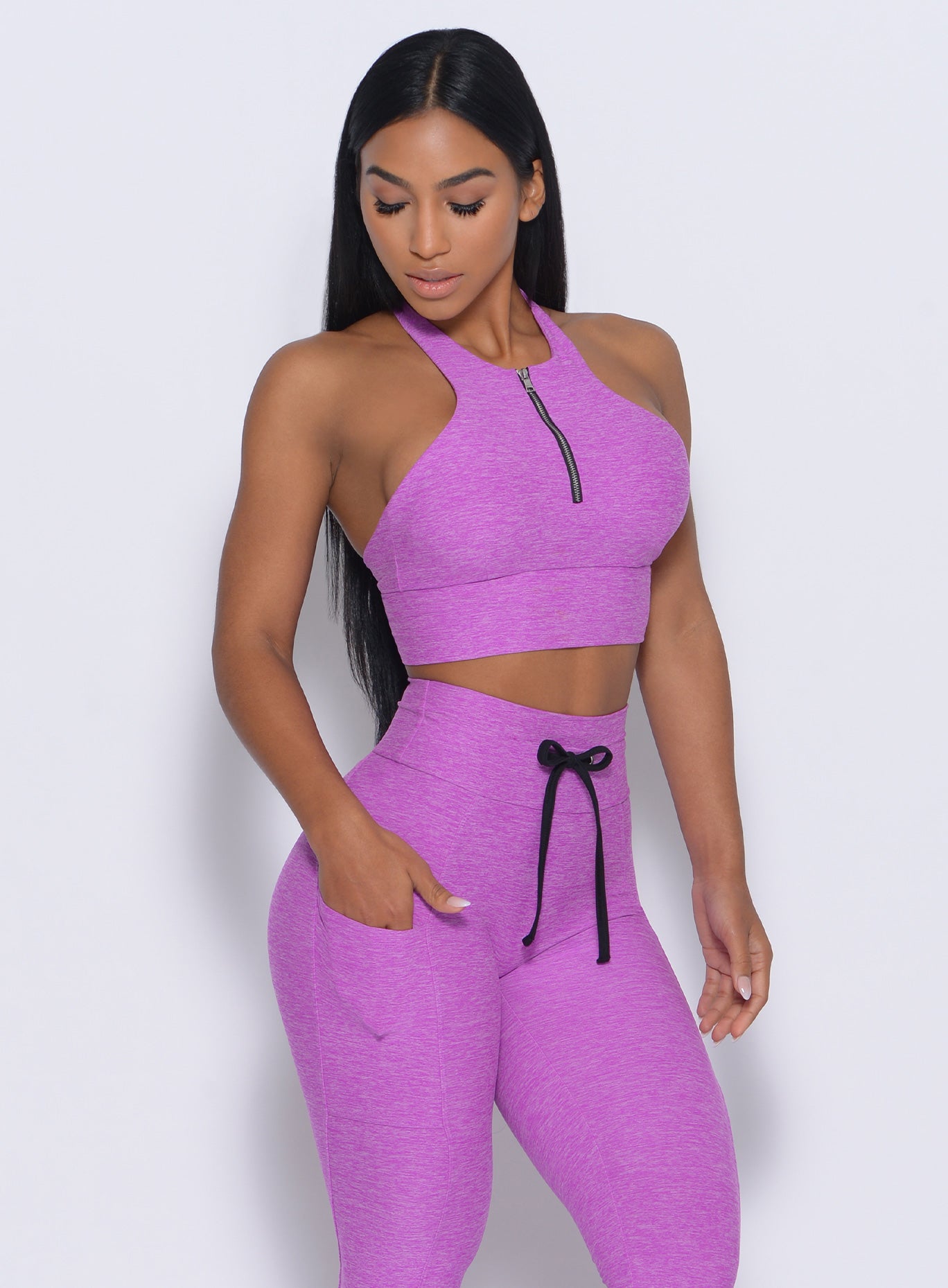 Front profile view of the model with her right hand in pocket wearing our edgy longline bra in purple rain color and a matching leggings