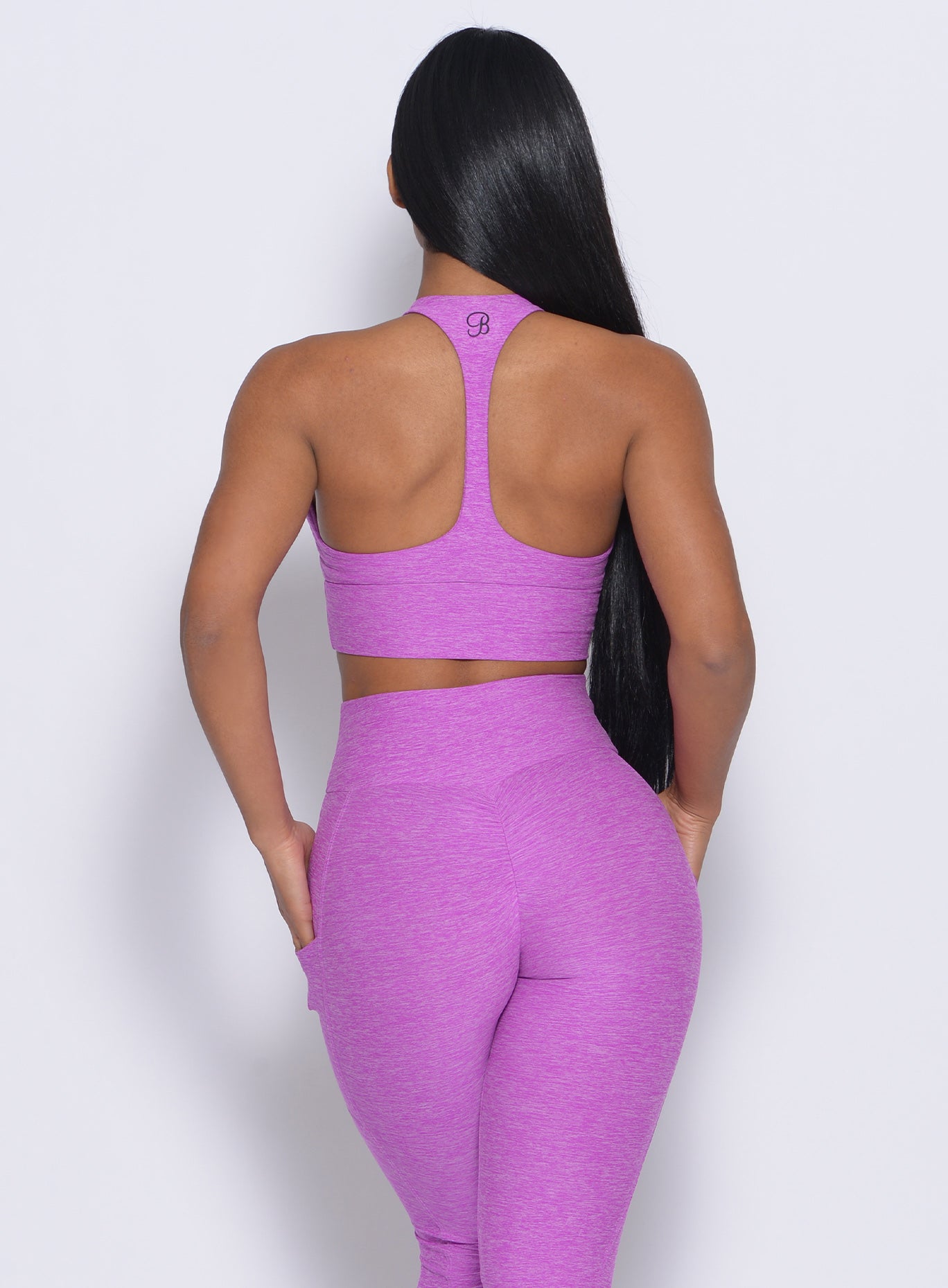 Back profile view of the model in our edgy longline bra in purple rain color and a matching leggings