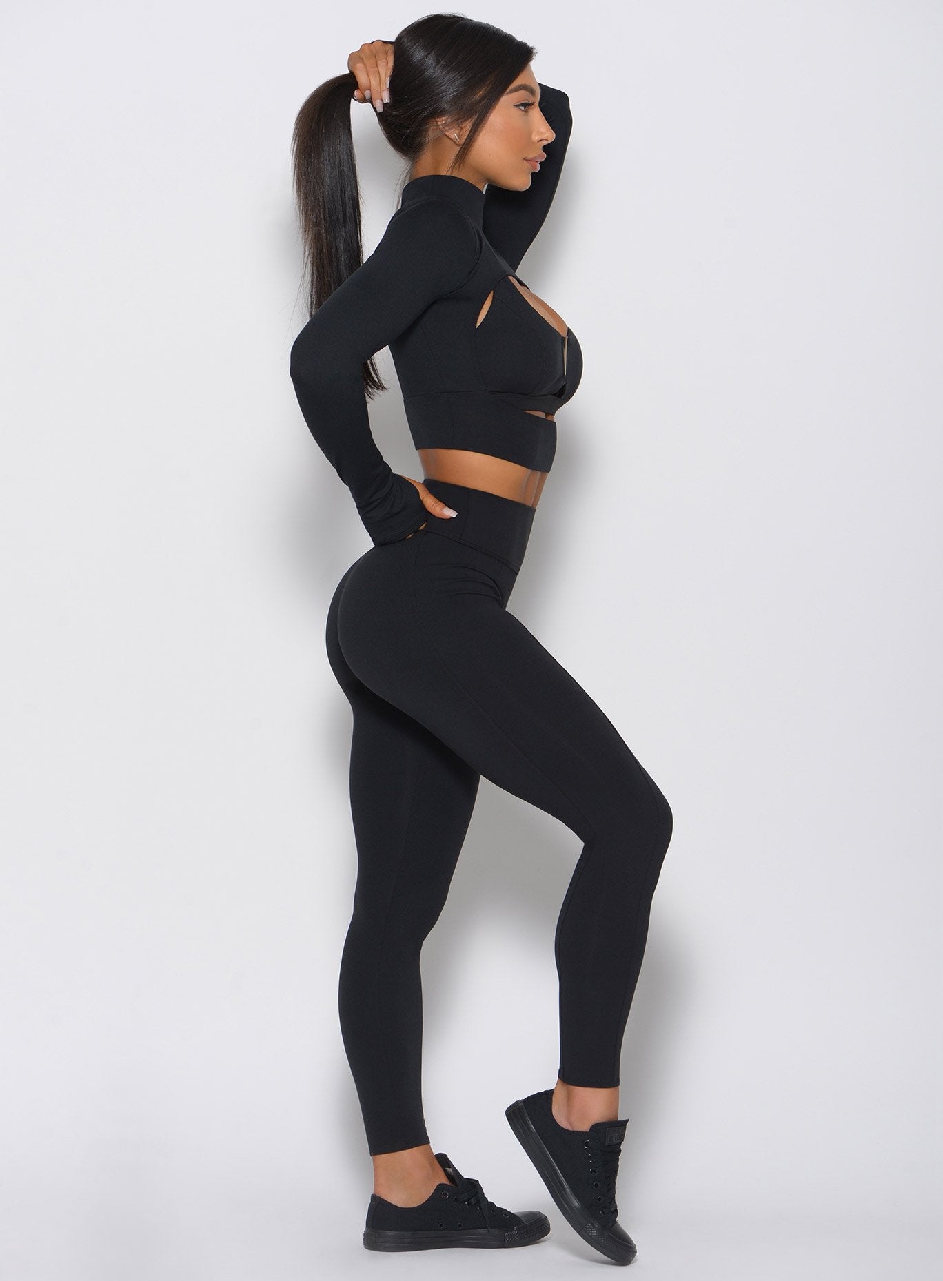Left side view of the model in a high waist black leggings with a V back design