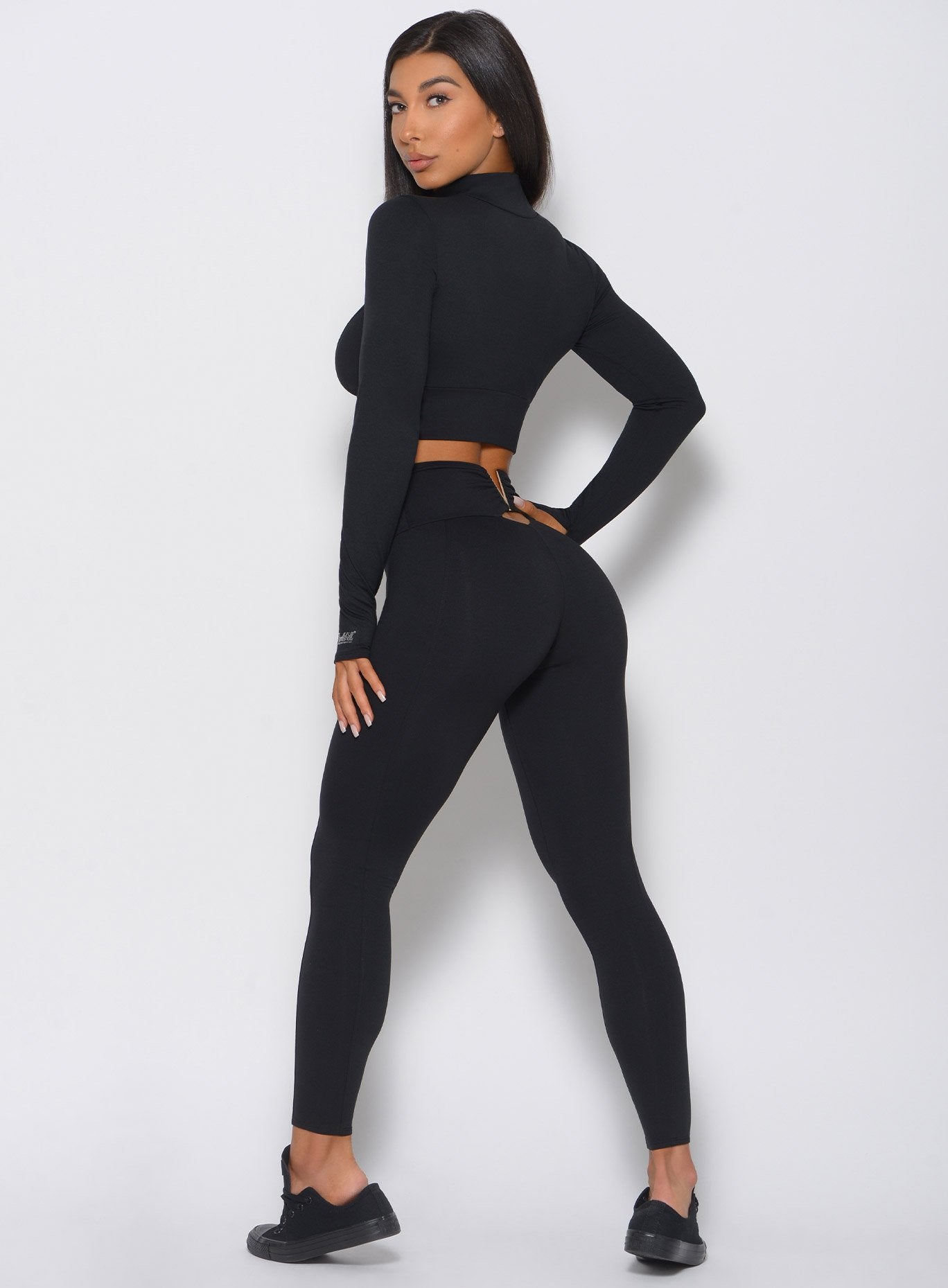 Left side view of the model in a high waist black leggings with a V back design