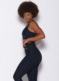 Left side profile view of a model facing to her left wearing our chevron sports bra in jet black color and a matching leggings