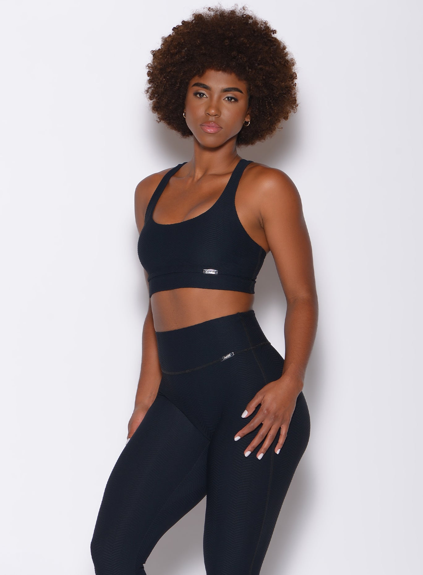 Front profile view of a model in our chevron sports bra in jet black color and a matching leggings