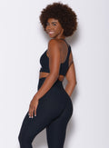Left side profile view of a model in our chevron sports bra in jet black color and a matching leggings