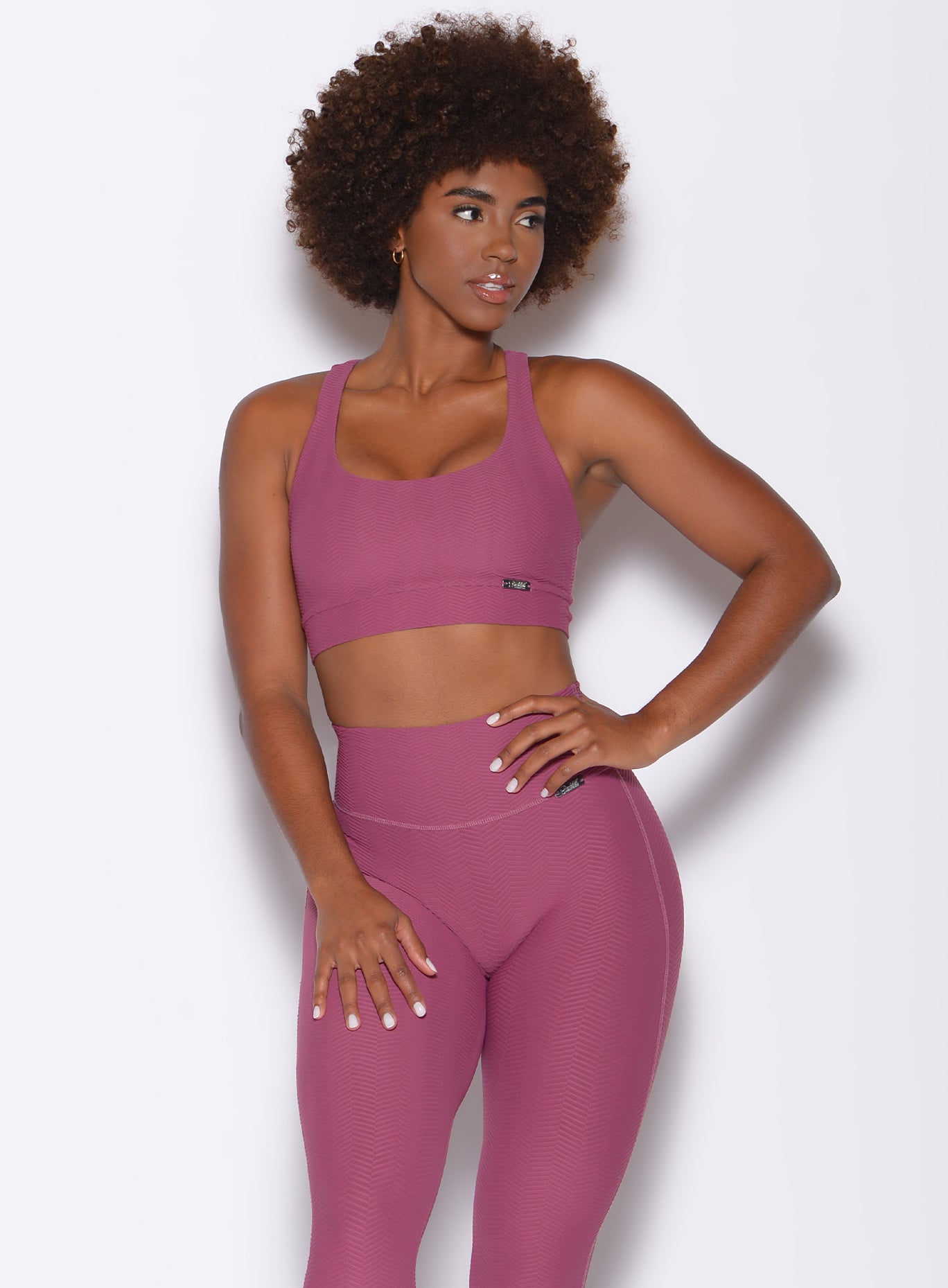 Front profile view of a model facing to her left wearing our chevron sports bra in rose wine color and a matching leggings