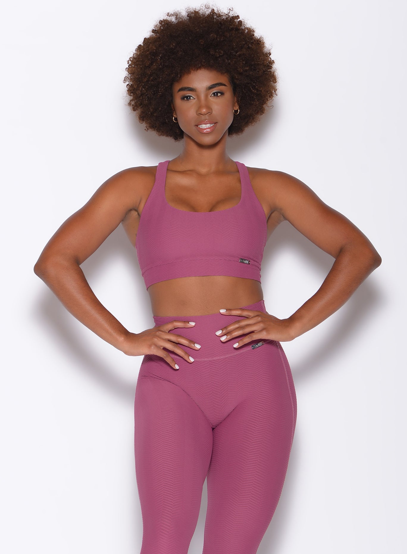 Front profile view of a model in our chevron sports bra in rose wine color and a matching leggings