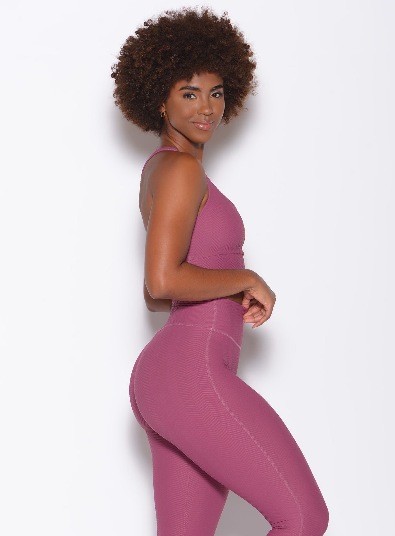 Right side profile view of a model facing to her right wearing our chevron sports bra in rose wine color and a matching leggings